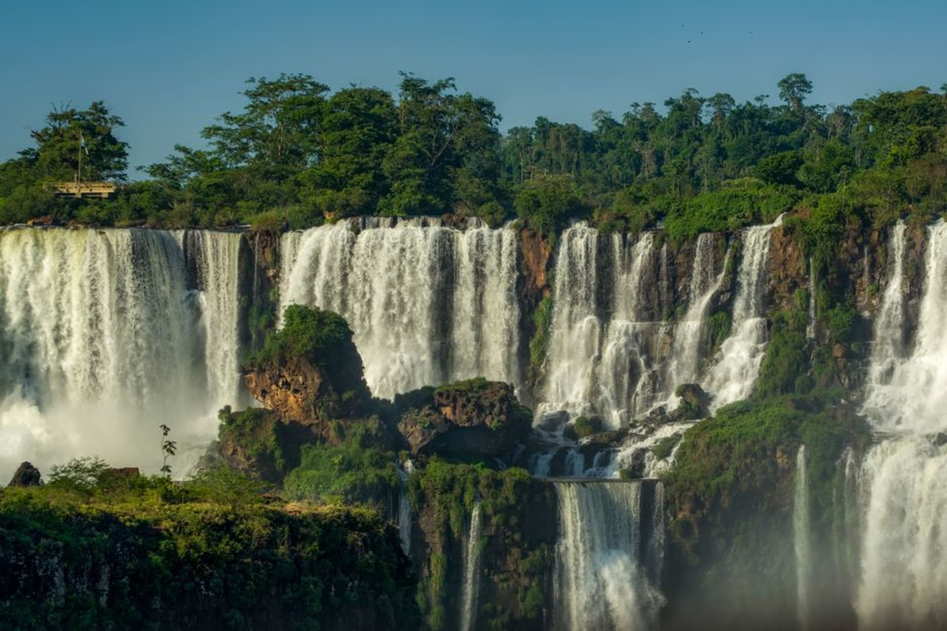 A waterfall cascading over rocks into a pool in Ybycui National Park, surrounded by dense subtropical forest