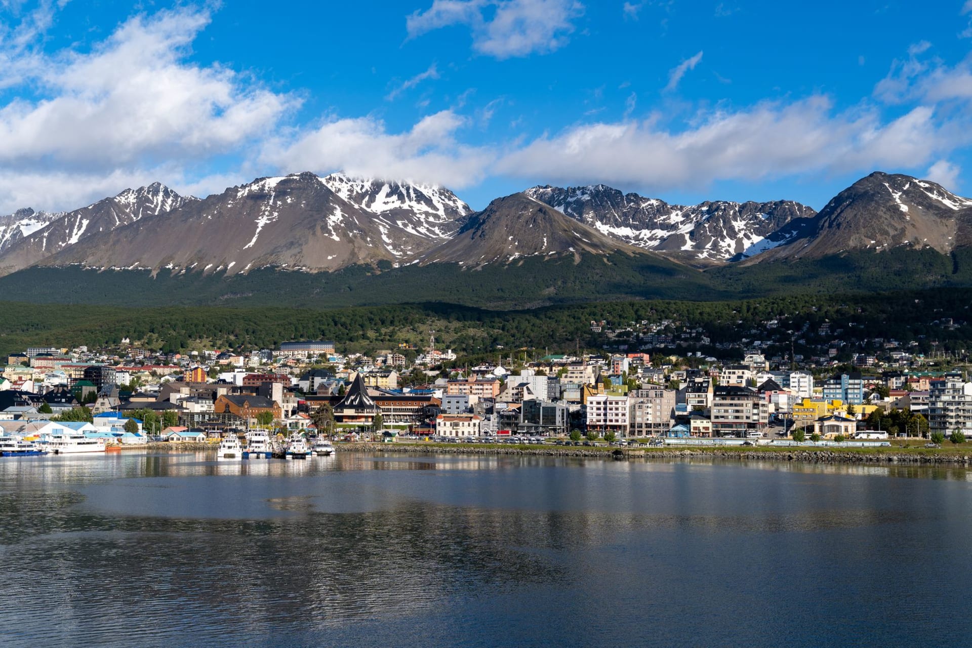 Puerto Natales's corrugated-iron storefronts lining the waterfront of Last Hope Sound under a dramatic Patagonian sky