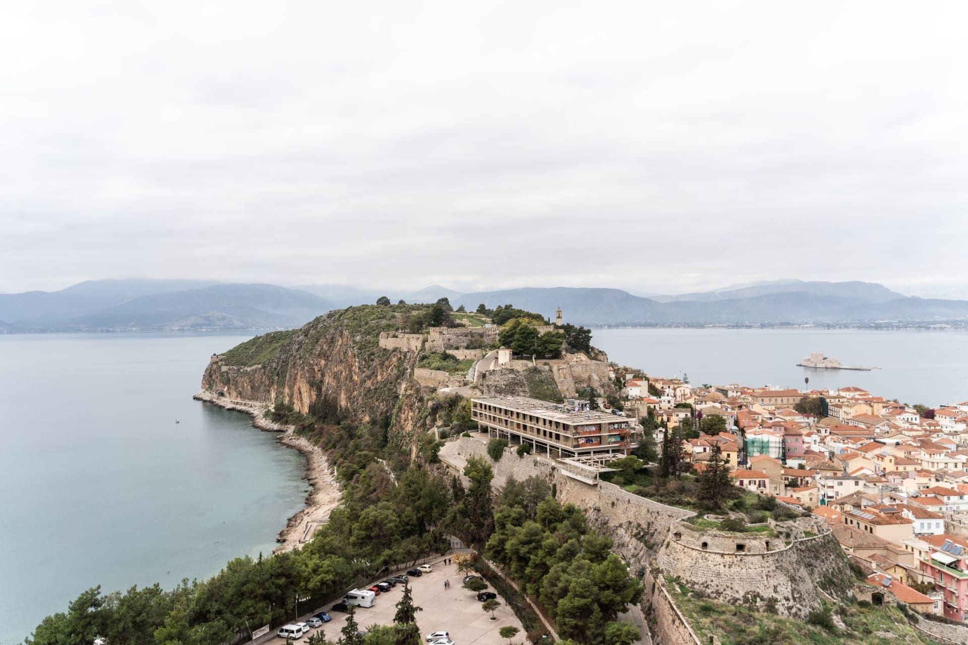 Acronauplia Fortress rising above the terracotta rooftops of Nafplio with the Argolic Gulf stretching behind it under afternoon light