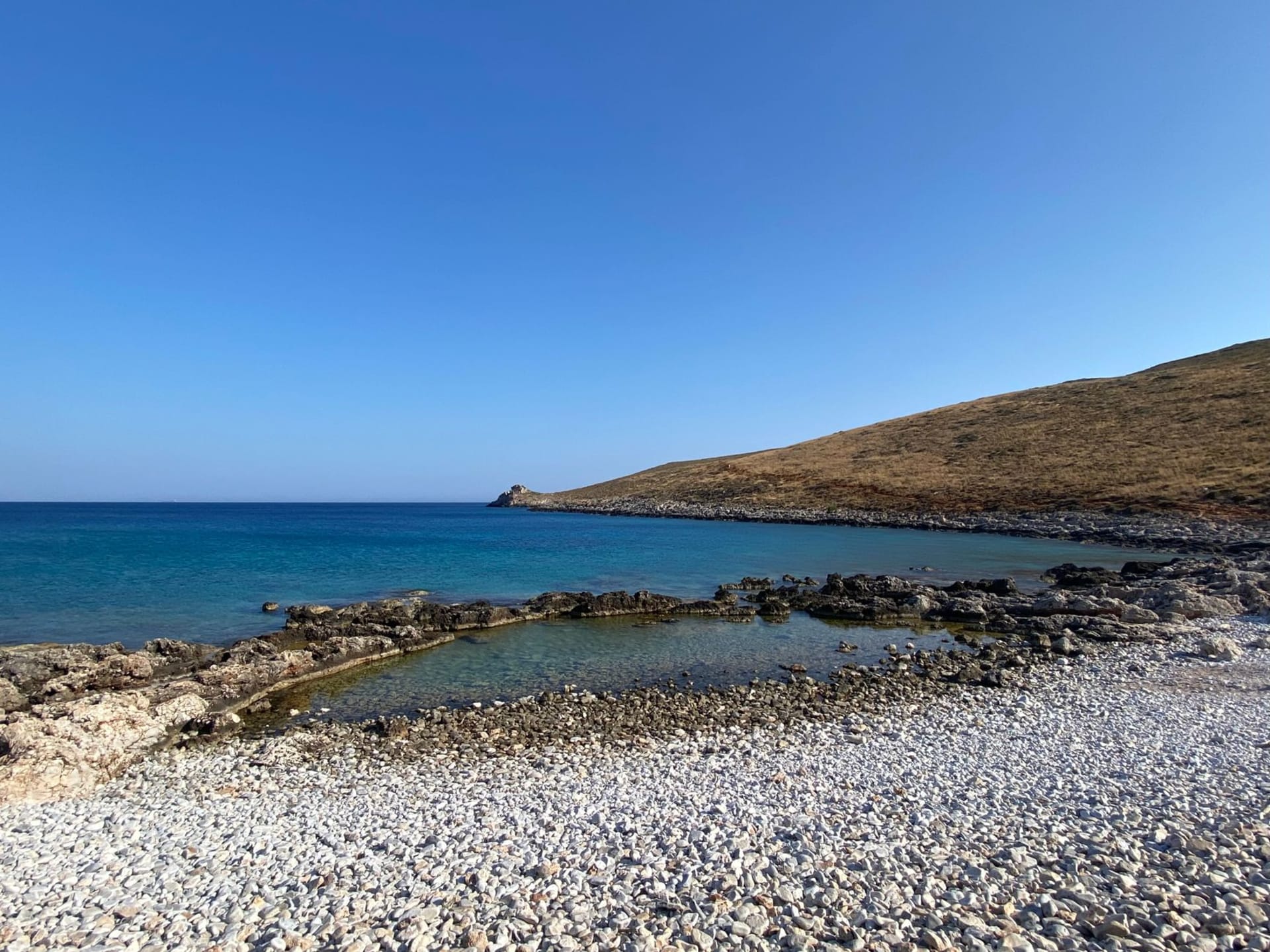 The near-perfect semicircle of Voidokilia Beach with turquoise water and pale sand seen from the hill above in Messinia