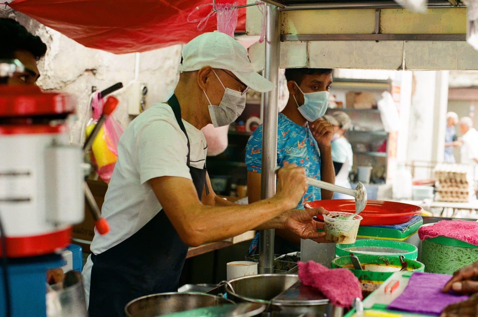 Street food vendor serving customers at a bustling hawker market in Penang, Malaysia