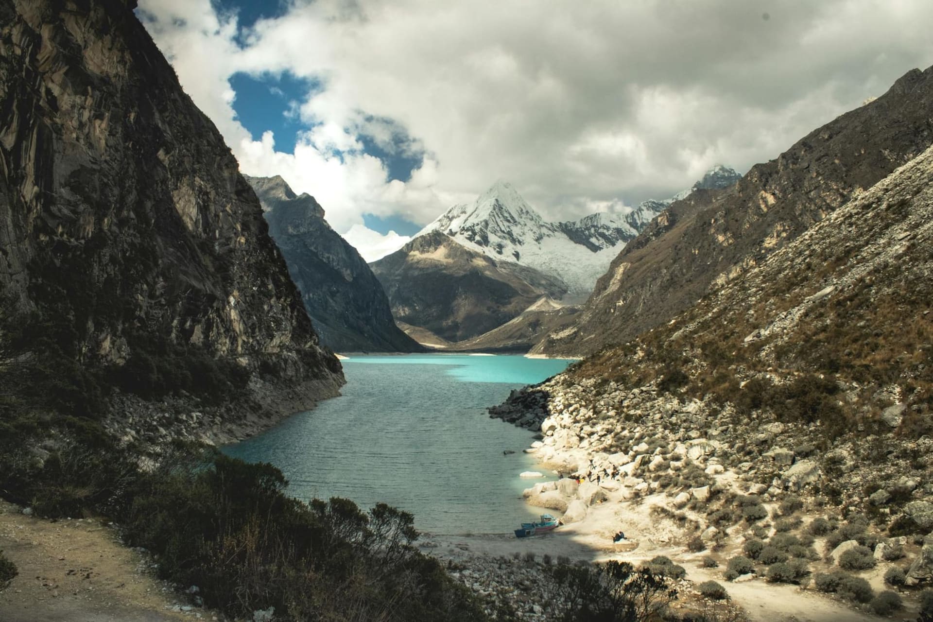 Snow-capped peaks of the Cordillera Blanca rising above the Rio Santa valley, with Huaraz's terracotta rooftops visible in the foreground under a deep blue Andean sky.