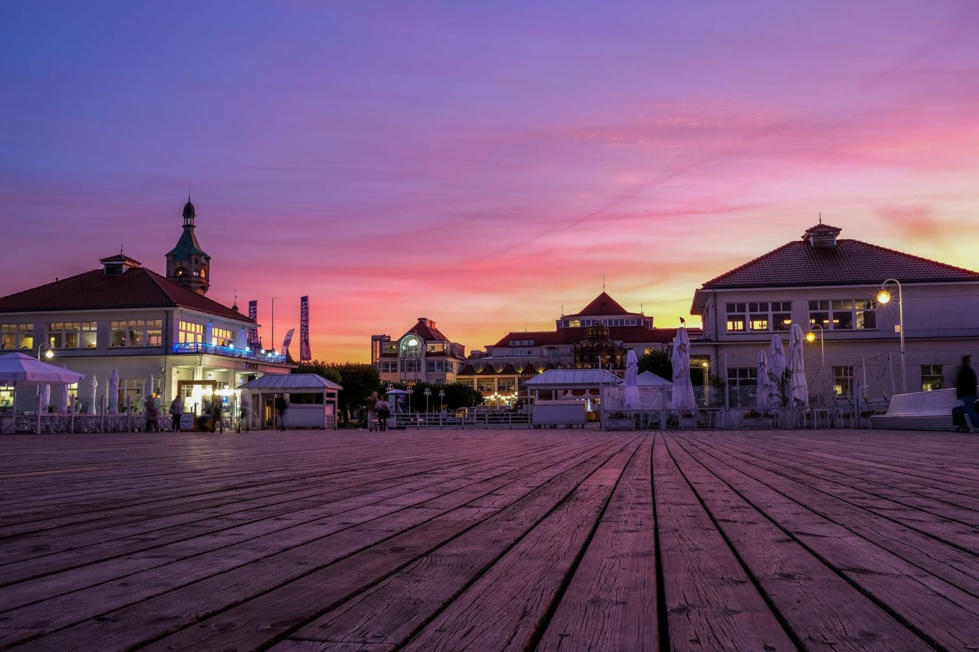 The 511-metre wooden pier of Sopot stretching into a silver-grey Baltic Sea, with the beach promenade and pastel resort facades visible along the shore.
