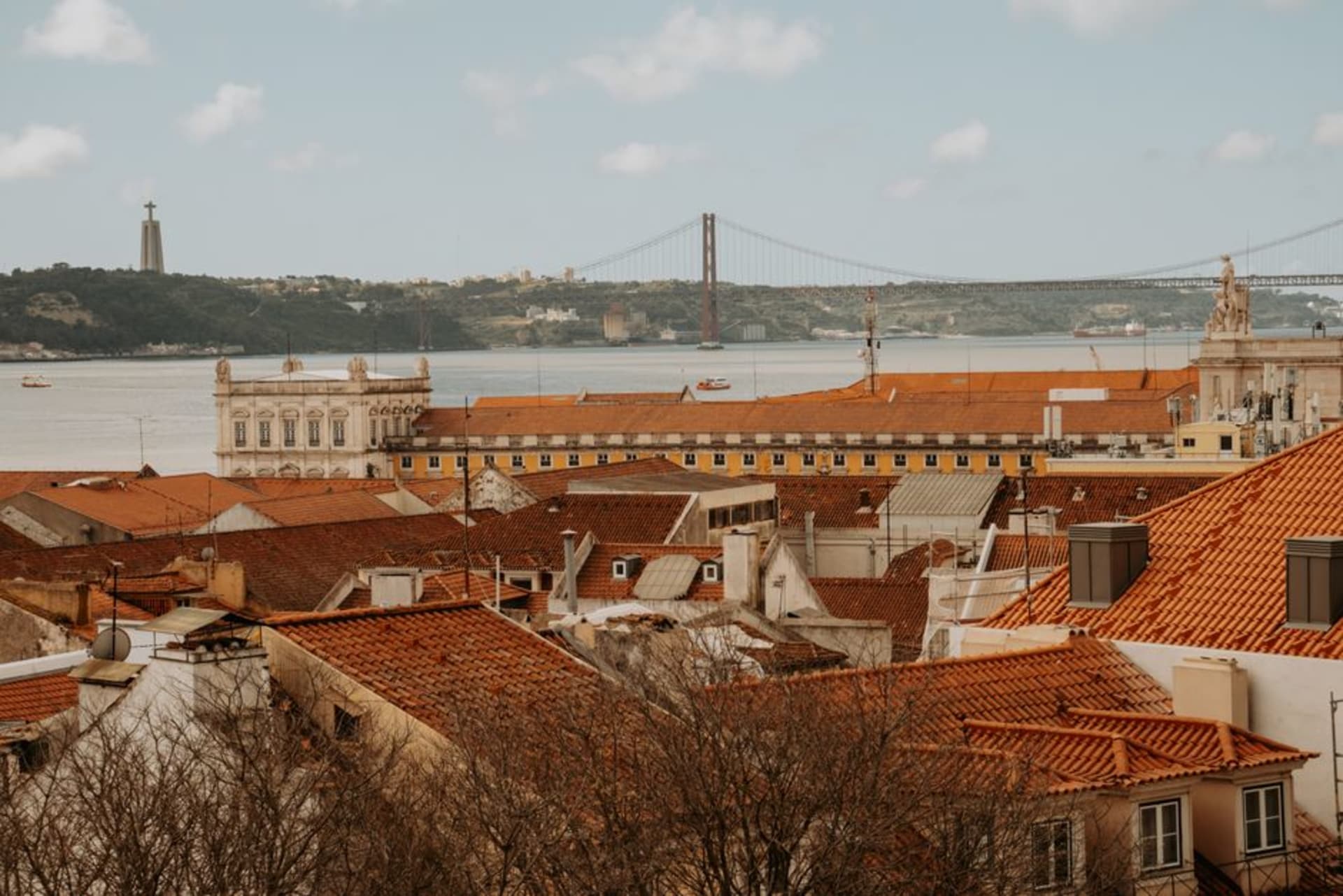 View across the Tejo river from Almada toward Lisbon's skyline with the 25 de Abril bridge