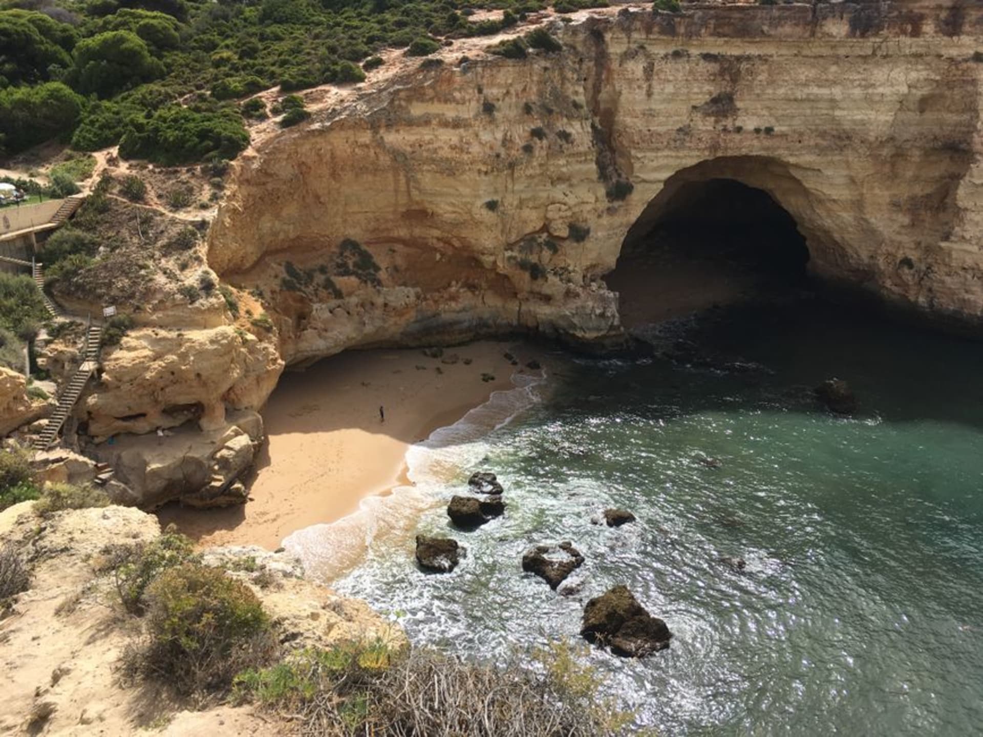 Carvoeiro's small crescent beach wedged between orange sandstone cliffs with whitewashed houses stacked above