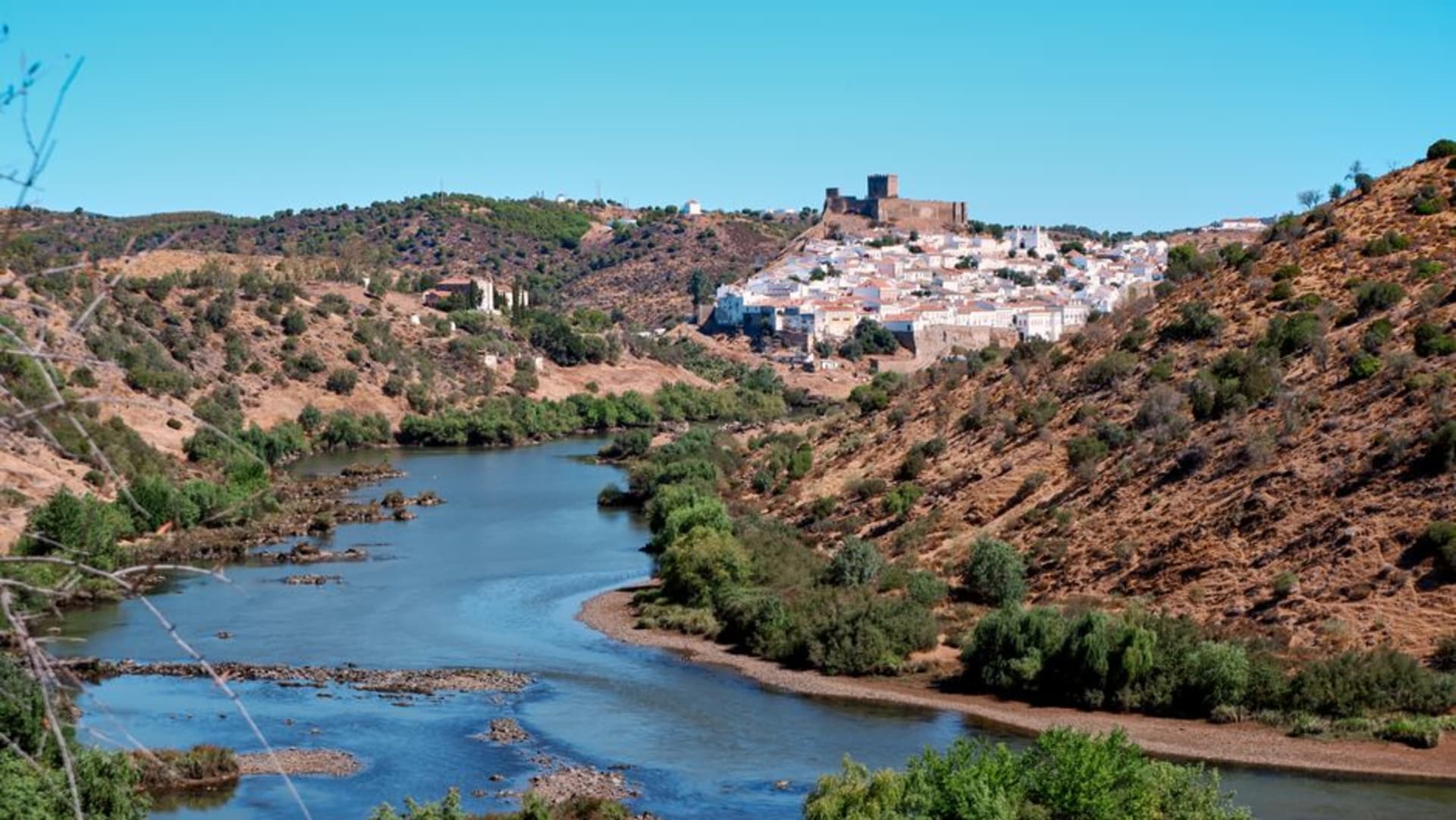Mértola's whitewashed houses cascading down a hillside to the Guadiana river