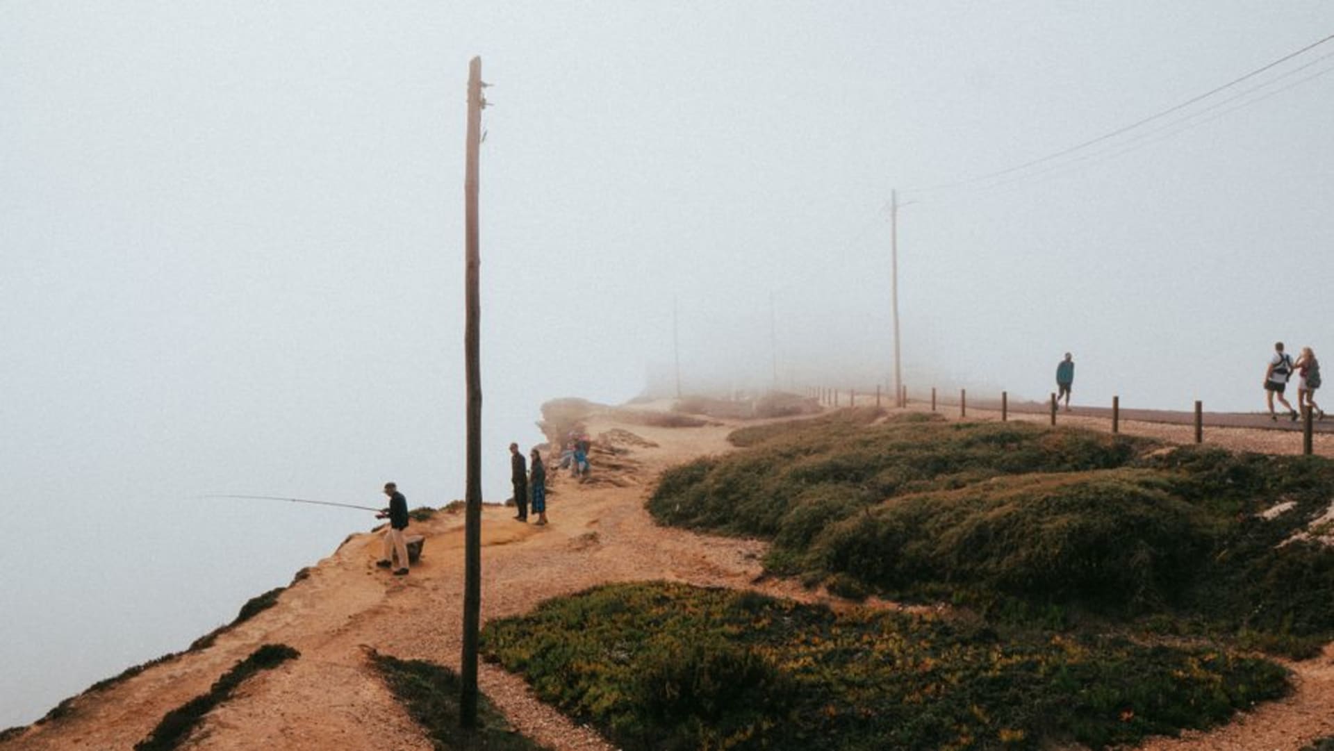 Dirt cliff-top trail of the Fishermen's Trail hugging the Atlantic coastline with waves crashing below