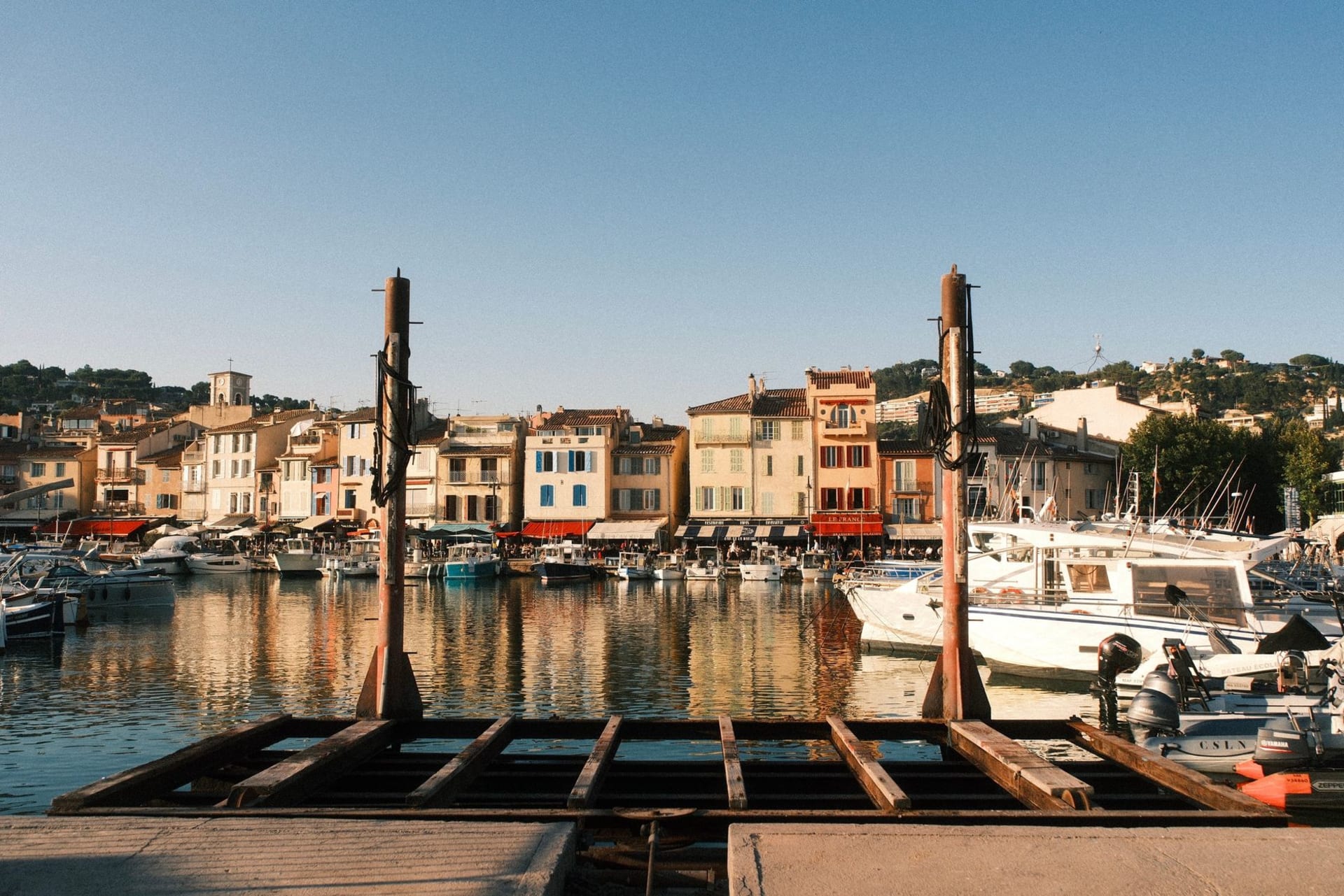 The colourful harbour of Cassis with fishing boats at anchor and the white limestone cliffs of Cap Canaille rising behind