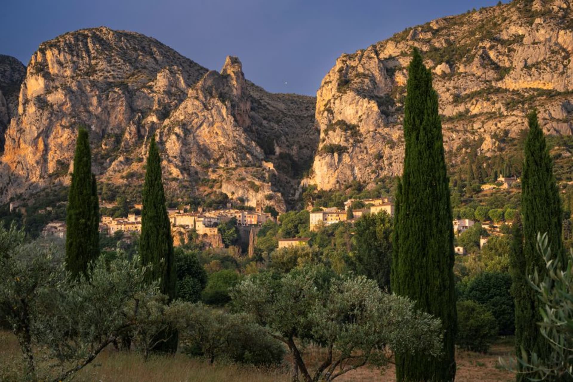 El pueblo de Moustiers-Sainte-Marie a los pies de acantilados calizos, con una estrella dorada suspendida en una cadena sobre los tejados
