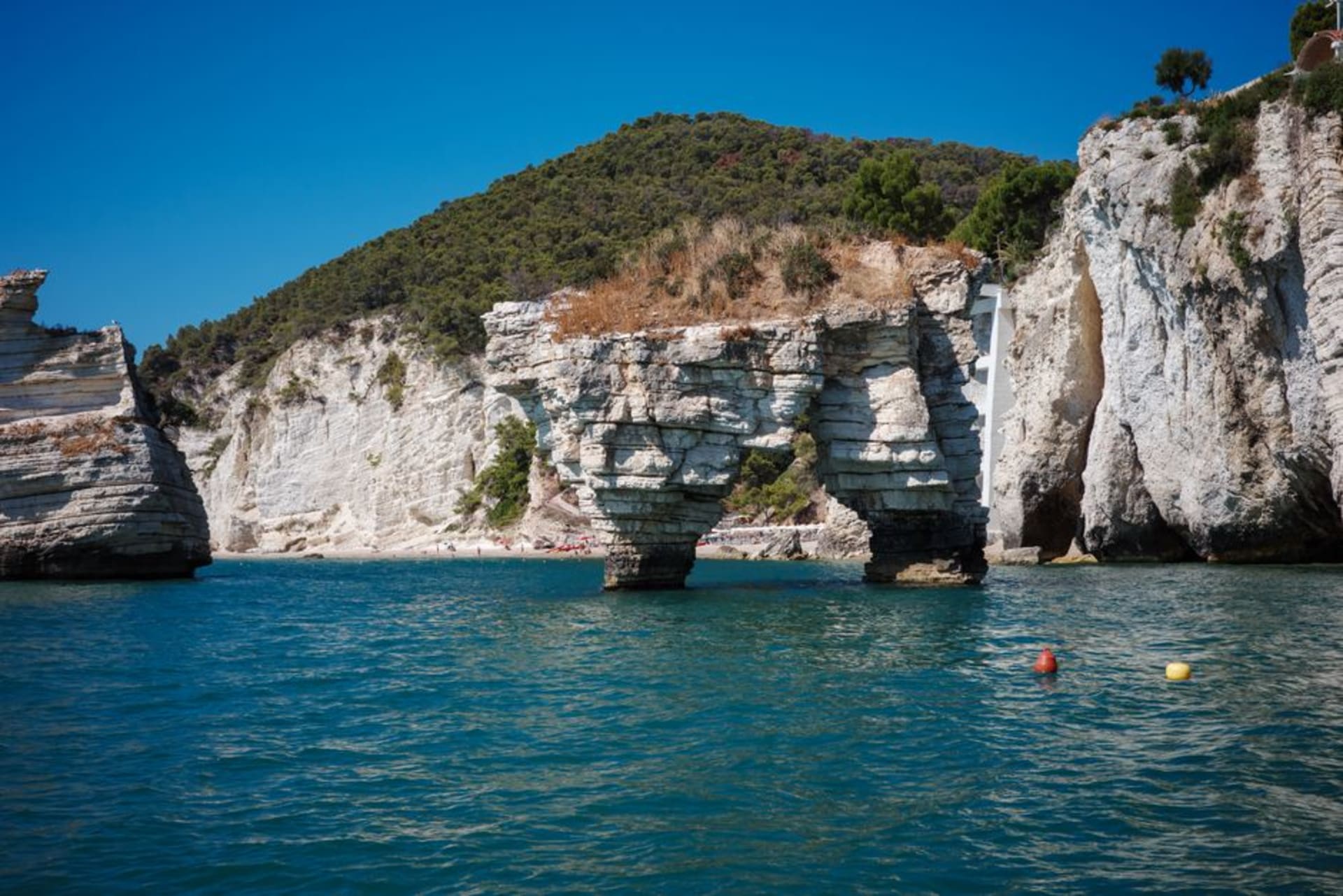 La crique de la Baia delle Zagare sur la côte du Gargano, deux stacks rocheux jumeaux s'élevant d'une eau turquoise entre des falaises calcaires blanches