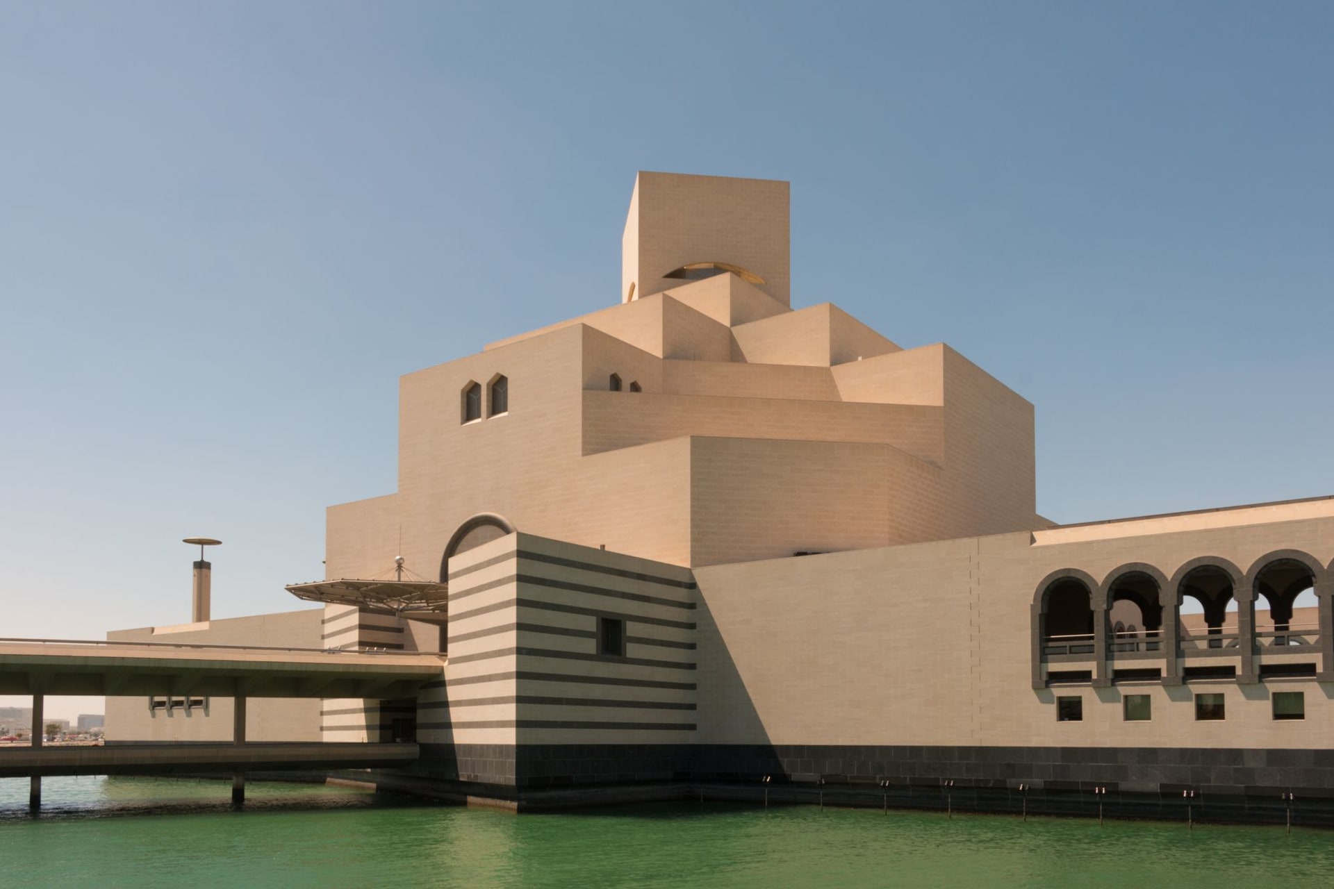 The angular white stone facade of the Museum of Islamic Art in Doha rising above the waterfront