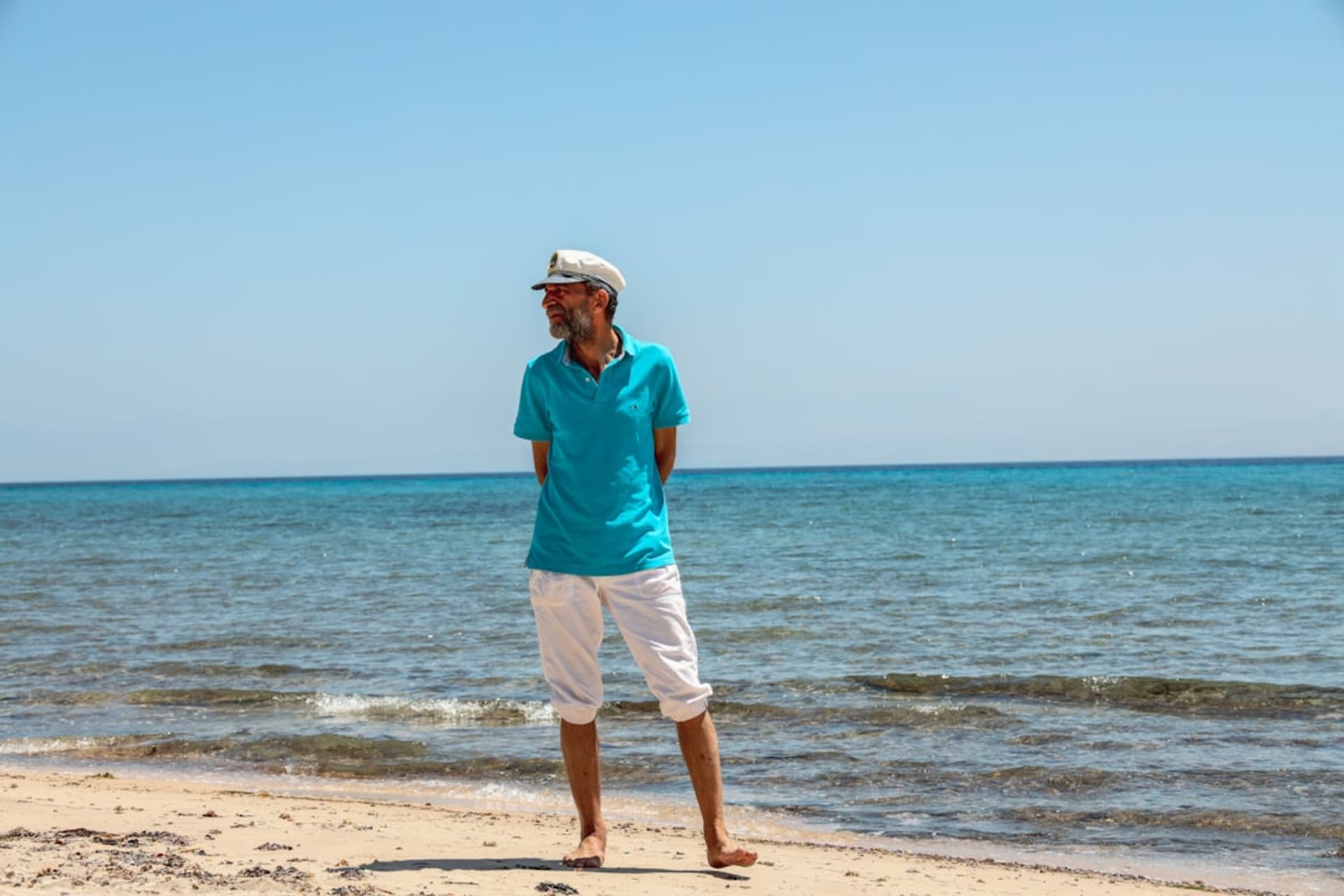 Un camp de huttes en feuilles de palmier sur le rivage de Nuweiba au crépuscule, avec les montagnes du Sinaï en arrière-plan et le littoral jordanien visible de l'autre côté du golfe d'Aqaba