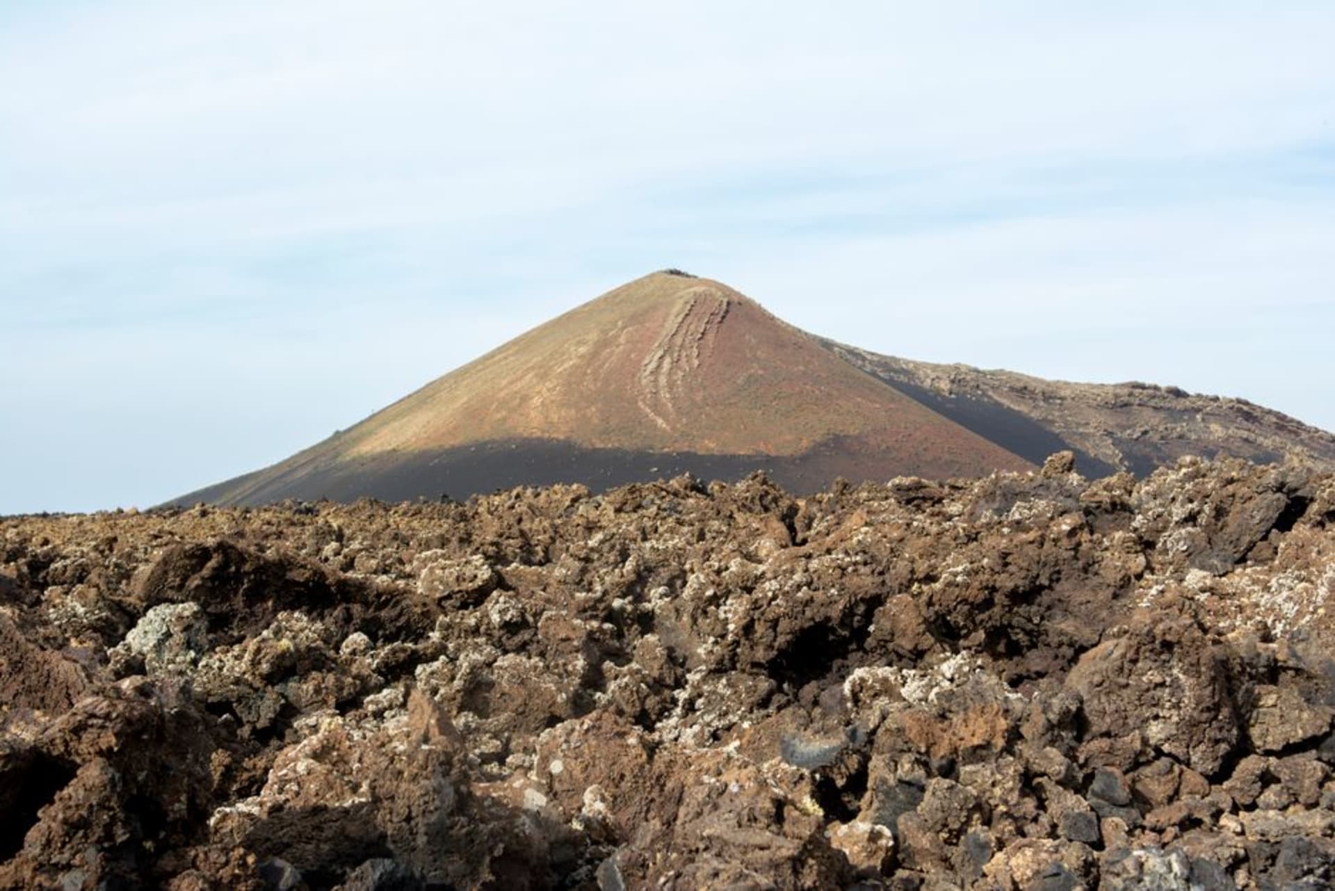 Les collines volcaniques arides de l'île de Zabargad s'élevant au-dessus d'une baie turquoise, vues depuis un bateau de croisière ancré
