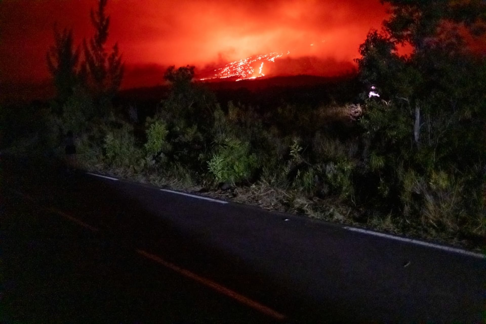 The white Notre-Dame des Laves church standing at the edge of a black lava field on the east coast of Réunion, tropical vegetation visible at the margin where the lava stopped