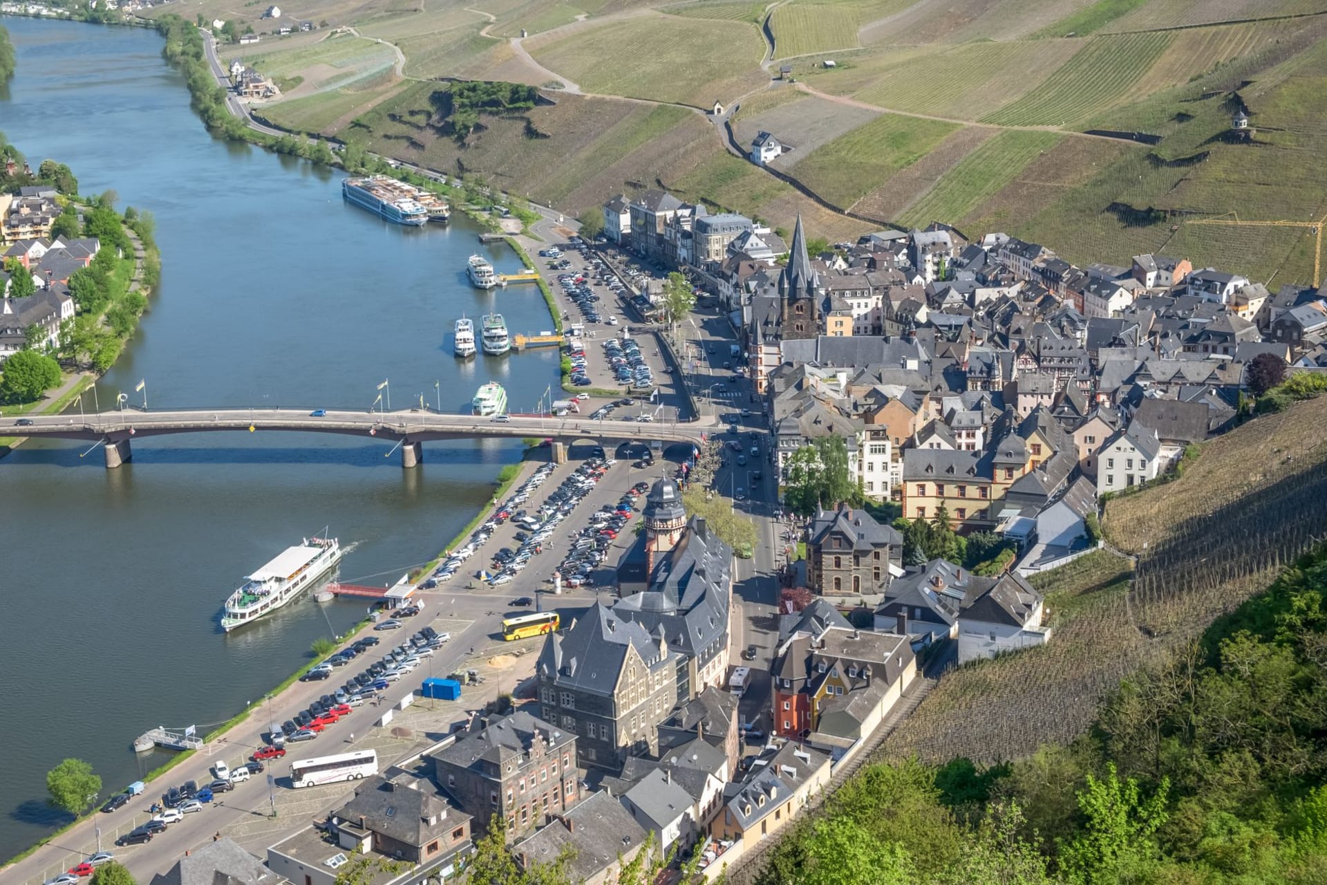 Rheinsteig hiking path winding through steep vineyard terraces high above the Rhine gorge with river traffic below