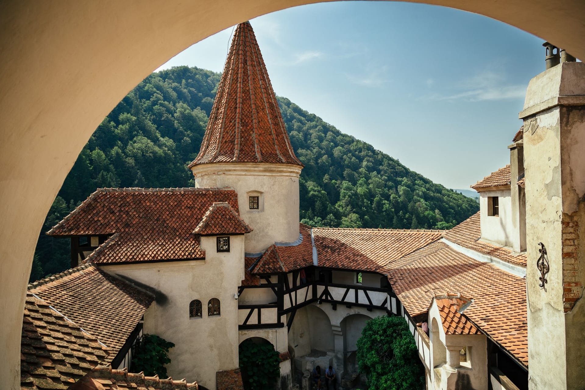 Le château de Bran se dressant au-dessus de la dense forêt de Transylvanie, ses tourelles blanches et ses toits sombres encadrés par des collines verdoyantes