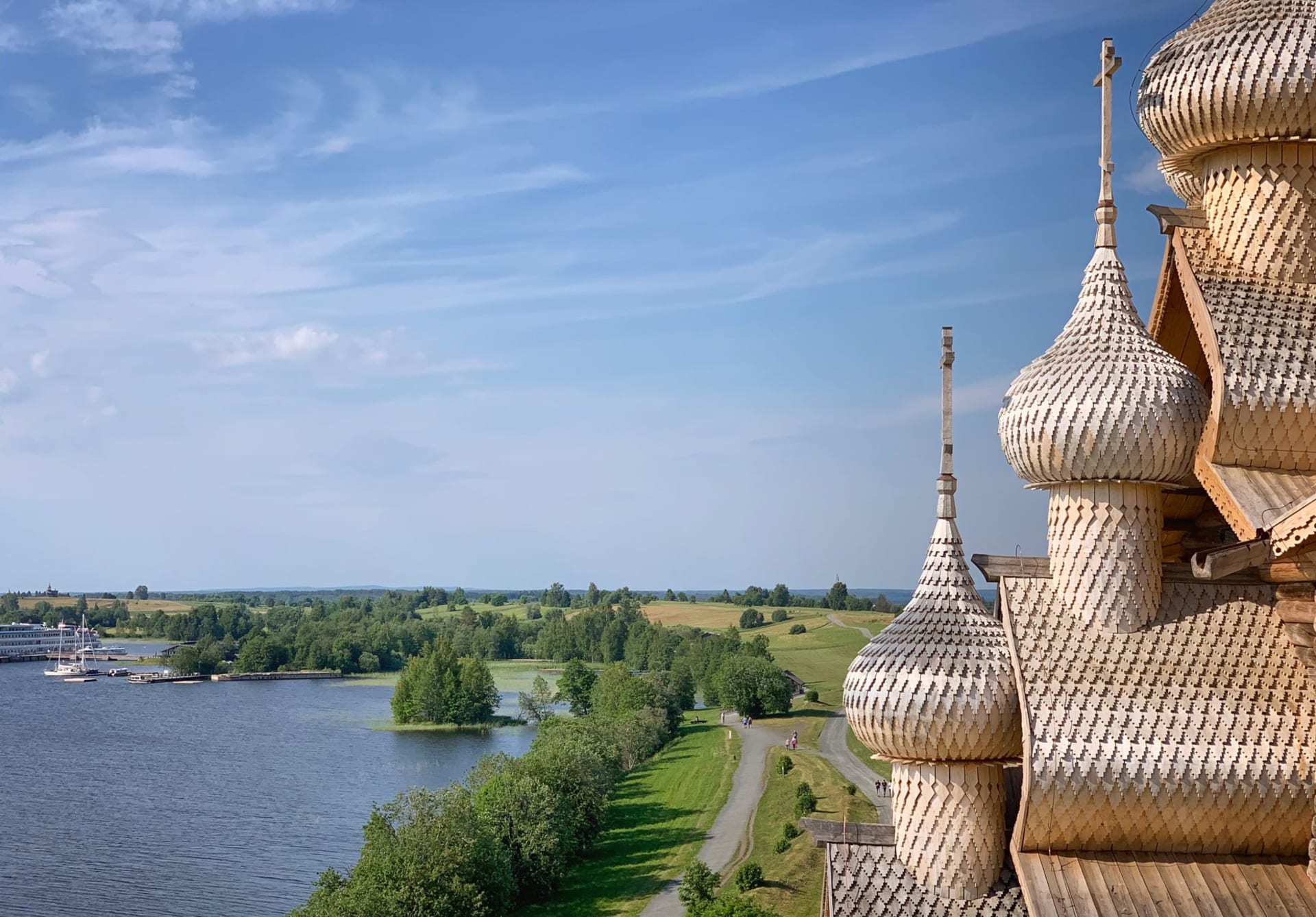 The silver aspen domes of the Church of the Transfiguration on Kizhi Island rising above a flat green meadow under a pale Karelian sky