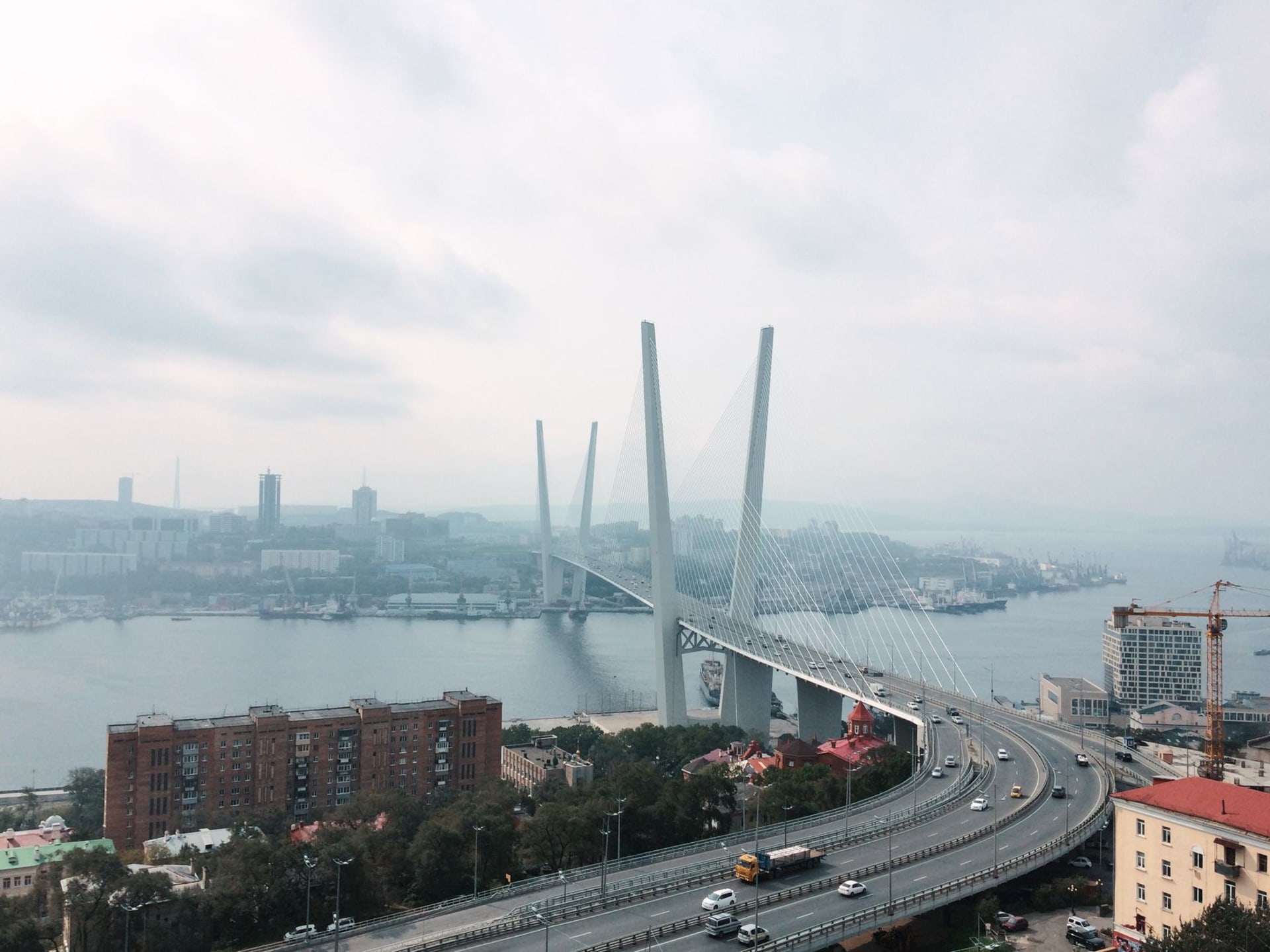 Vladivostok's Golden Horn Bay and its illuminated suspension bridge glowing under a dramatic sunset sky, seen from the hills above the city