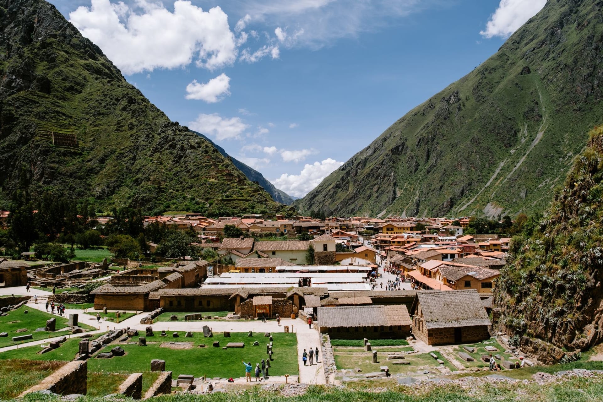 Sweeping aerial view of the Sacred Valley floor with patchwork agricultural fields and Andean peaks rising sharply on both sides