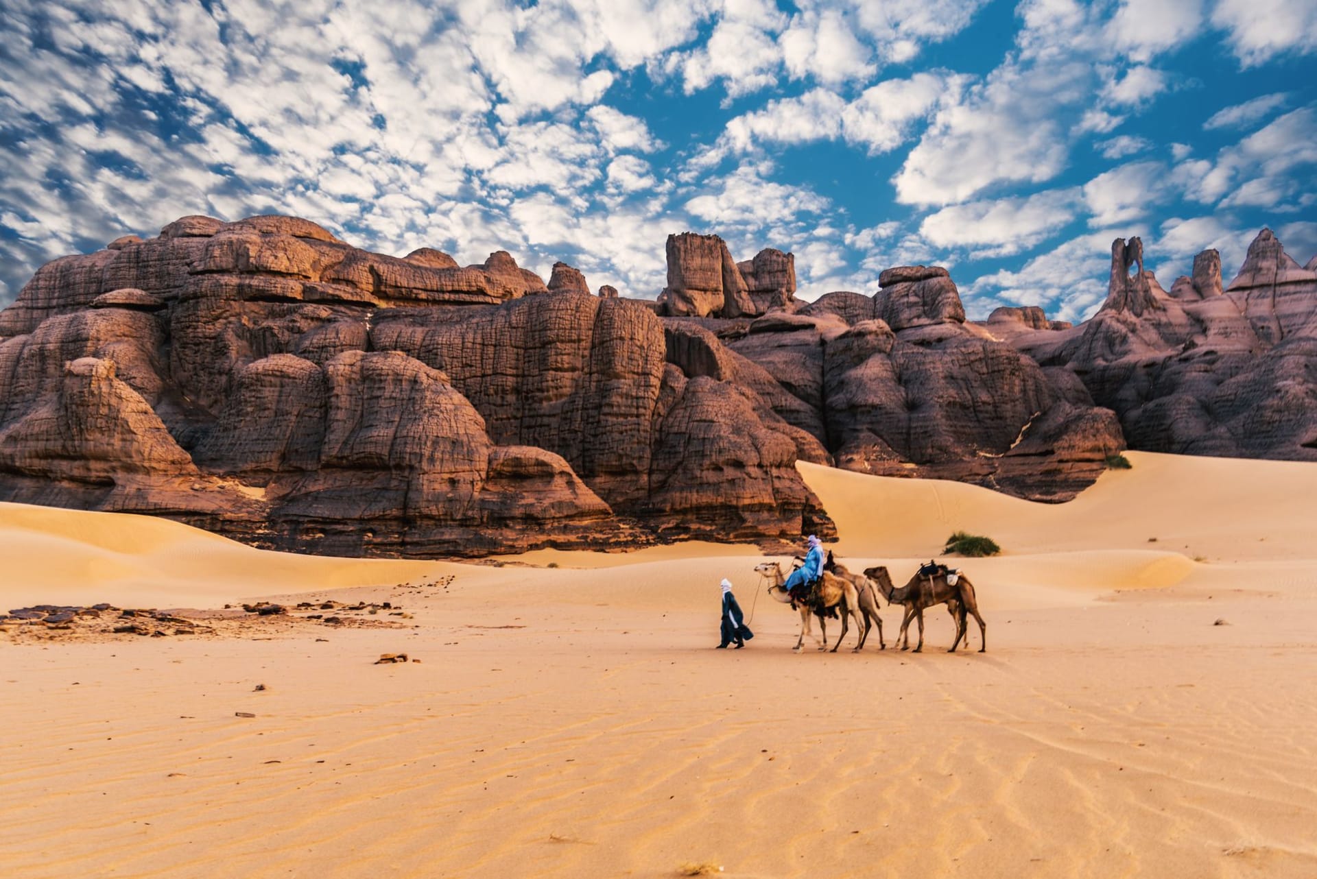Black volcanic peaks of the Hoggar Mountains rising dramatically from the flat desert floor near Tamanrasset at sunset