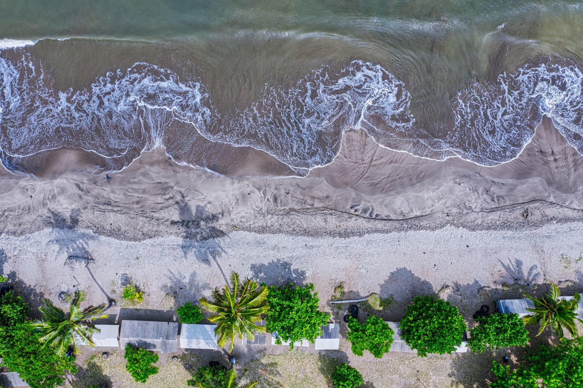 Richmond Beach's expanse of black volcanic sand with heavy surf and the green volcanic hills of northern Saint Vincent rising in the background