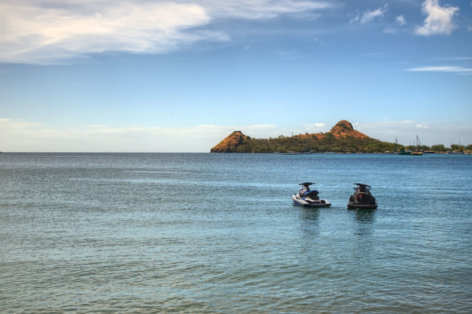 Clifton Harbor on Union Island with colorful fishing boats and a kite surfer arcing high above the water in strong trade winds