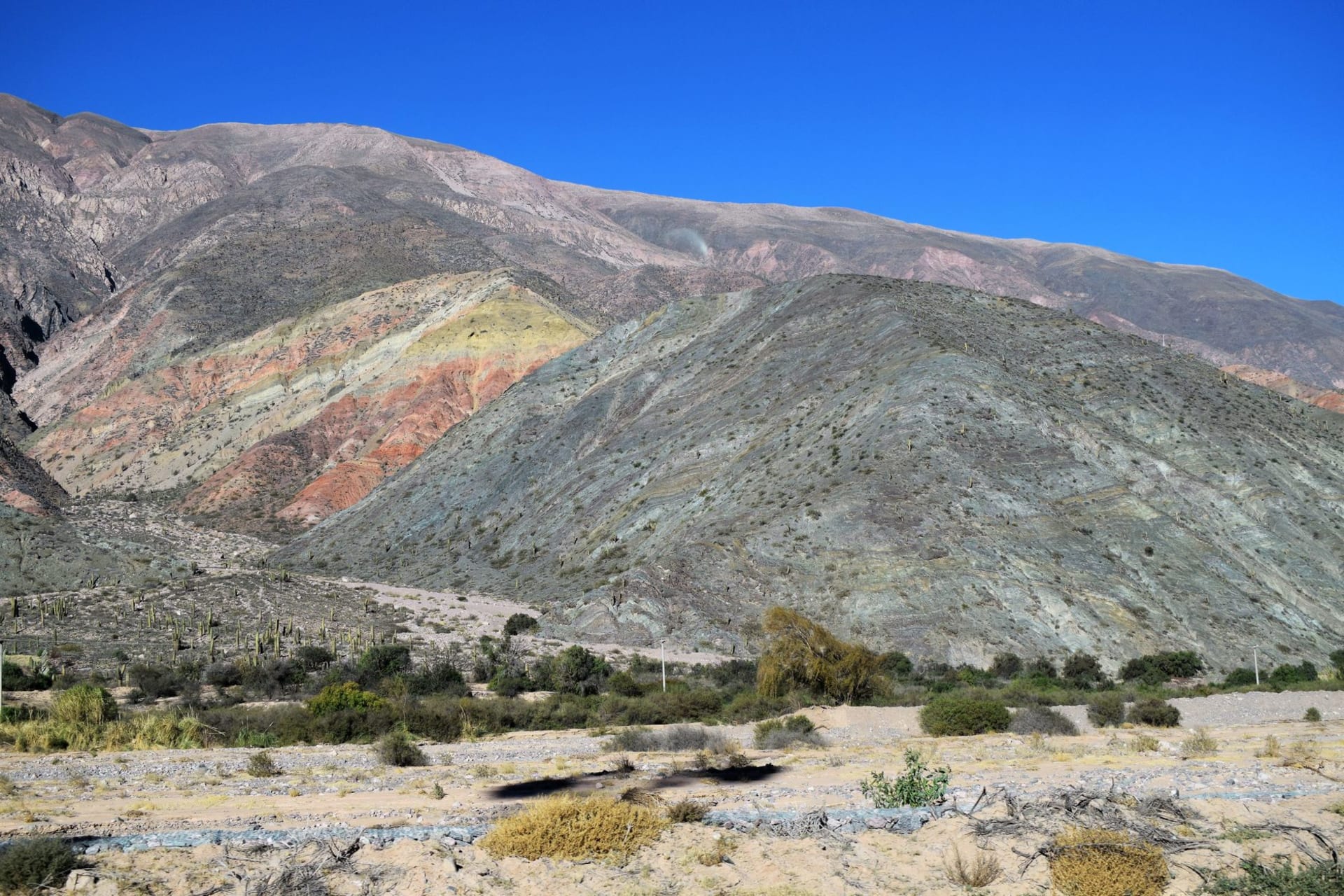 The steep cobblestone streets of Humahuaca rising between whitewashed and ochre adobe walls toward the independence monument on the hill above