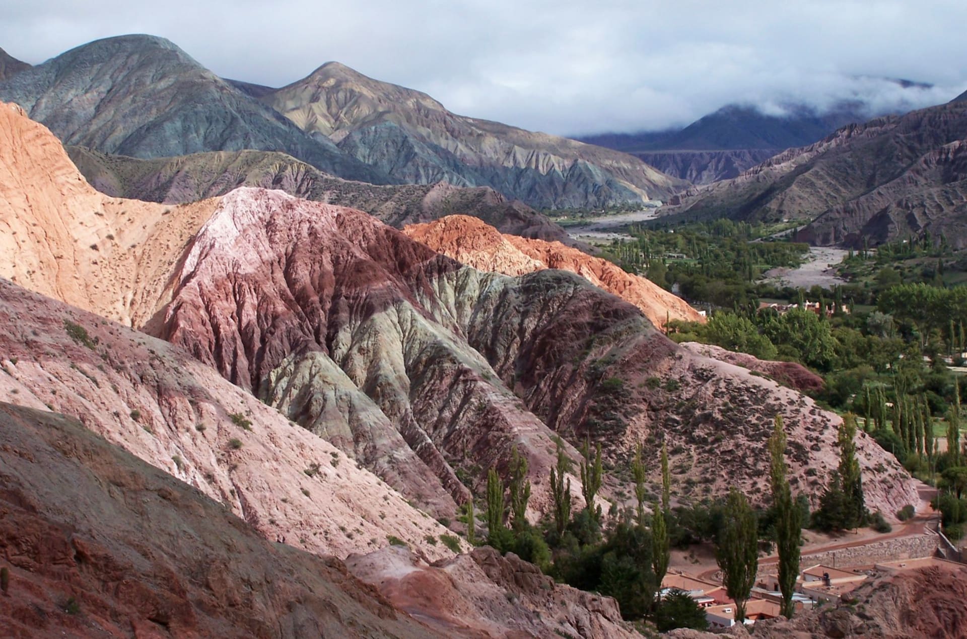 Narrow canyon road cutting through the vibrantly layered rust, ochre and violet hills of the Quebrada de Humahuaca in northwest Argentina
