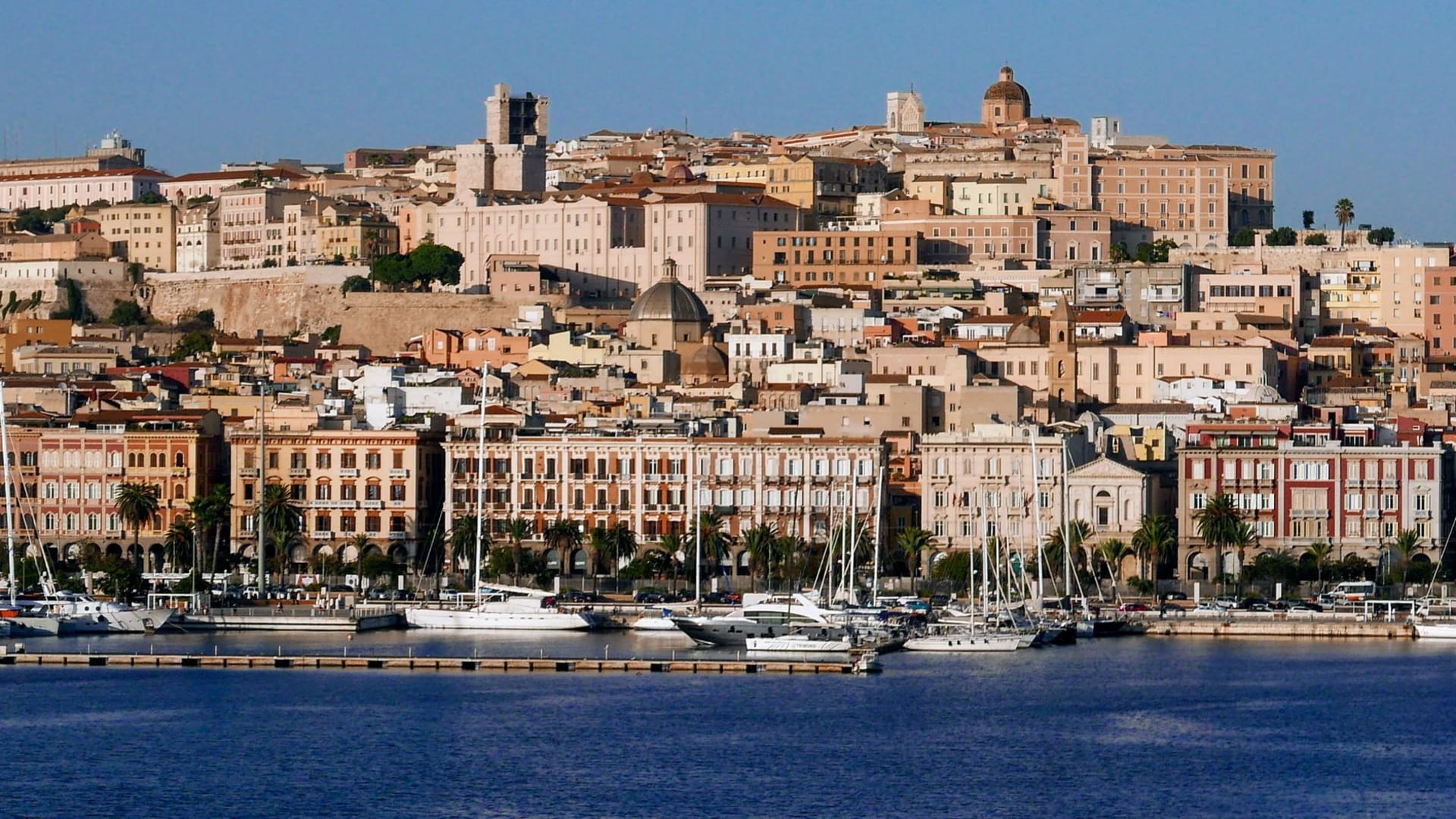 Cagliari's historic Castello district rising above the city's terracotta rooftops toward a deep blue Mediterranean sky