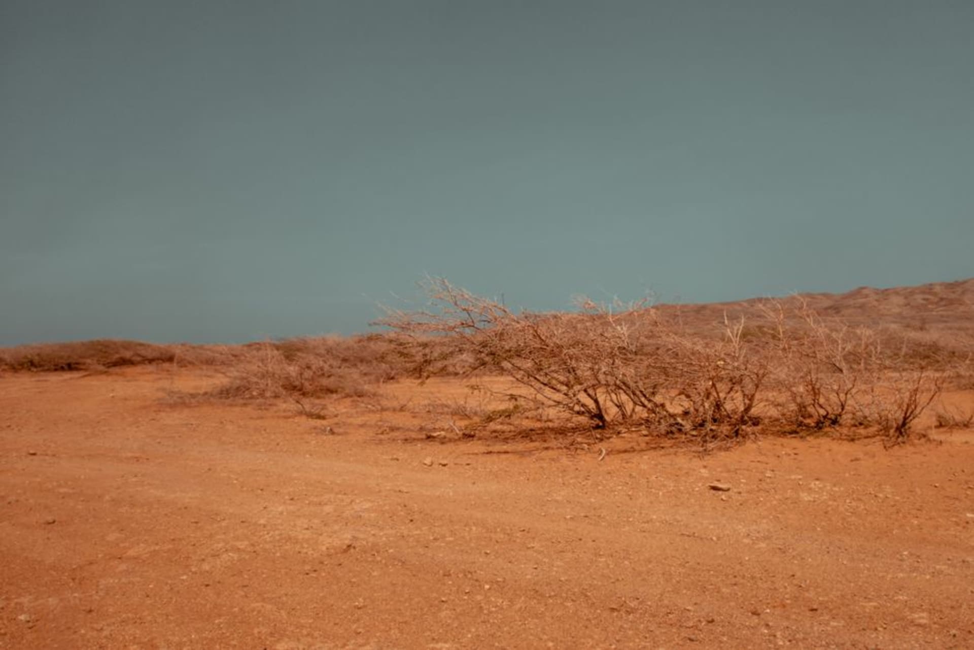 Orange sand dunes of the Lompoul desert in Senegal at golden hour, with sparse dry grass along the ridgelines