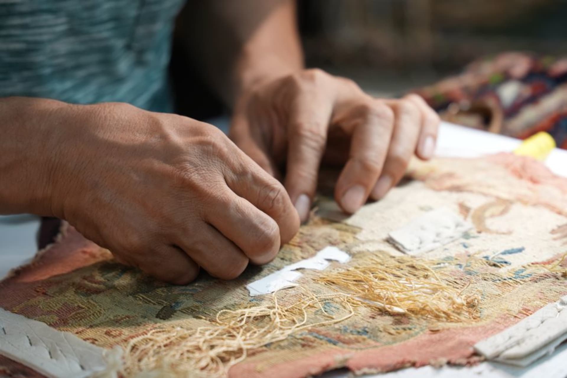 A weaver at a large vertical loom working on a colorful tapestry at the Manufacture Sénégalaise des Arts Décoratifs in Thiès