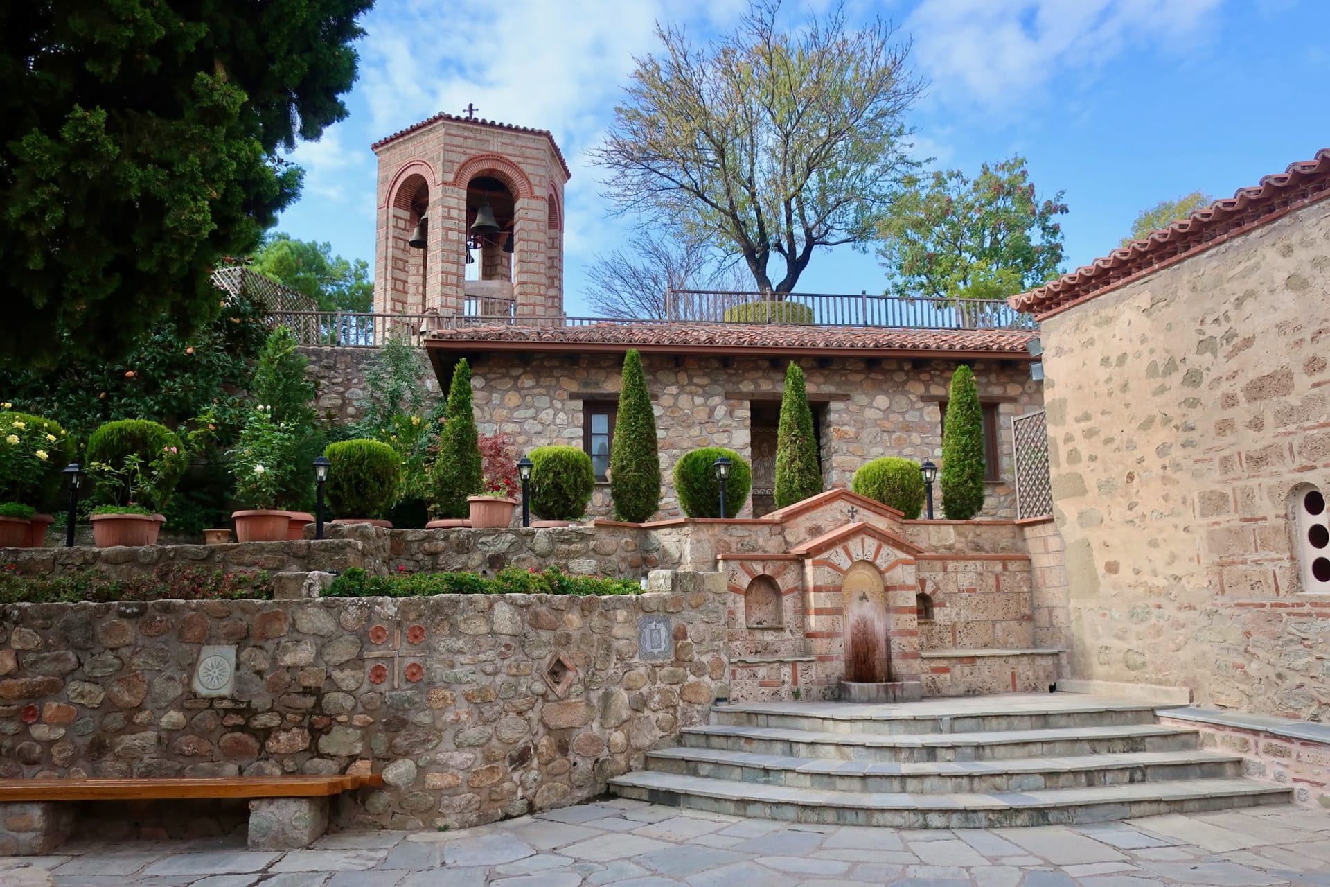 The white marble Church of the Virgin at Studenica Monastery glowing against a backdrop of dense green forest in a quiet Serbian valley, its Romanesque-Byzantine façade carved with interlacing stone reliefs