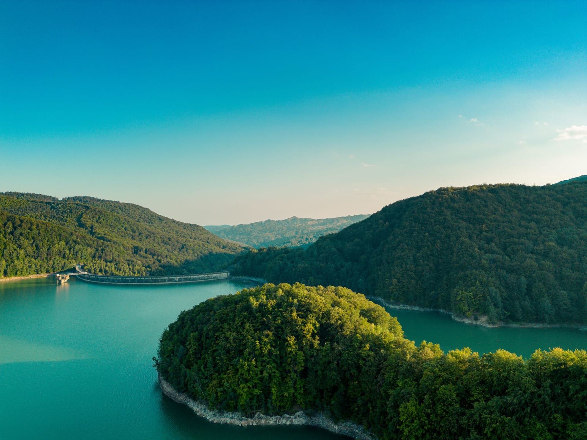 Aerial-style view of the Uvac River carving deep green horseshoe meanders between steep limestone cliffs in southwestern Serbia under a clear summer sky