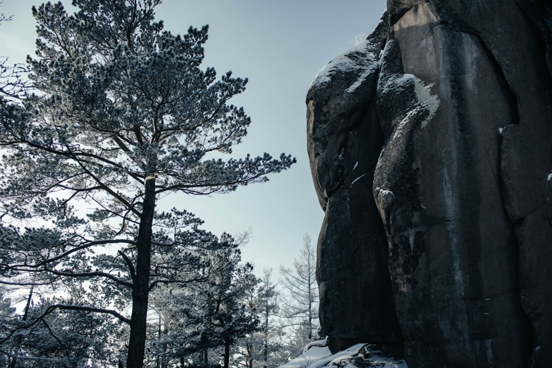 Granite stone pillars of Stolby Nature Reserve rising above Siberian taiga, the city visible as a faint line in the valley below