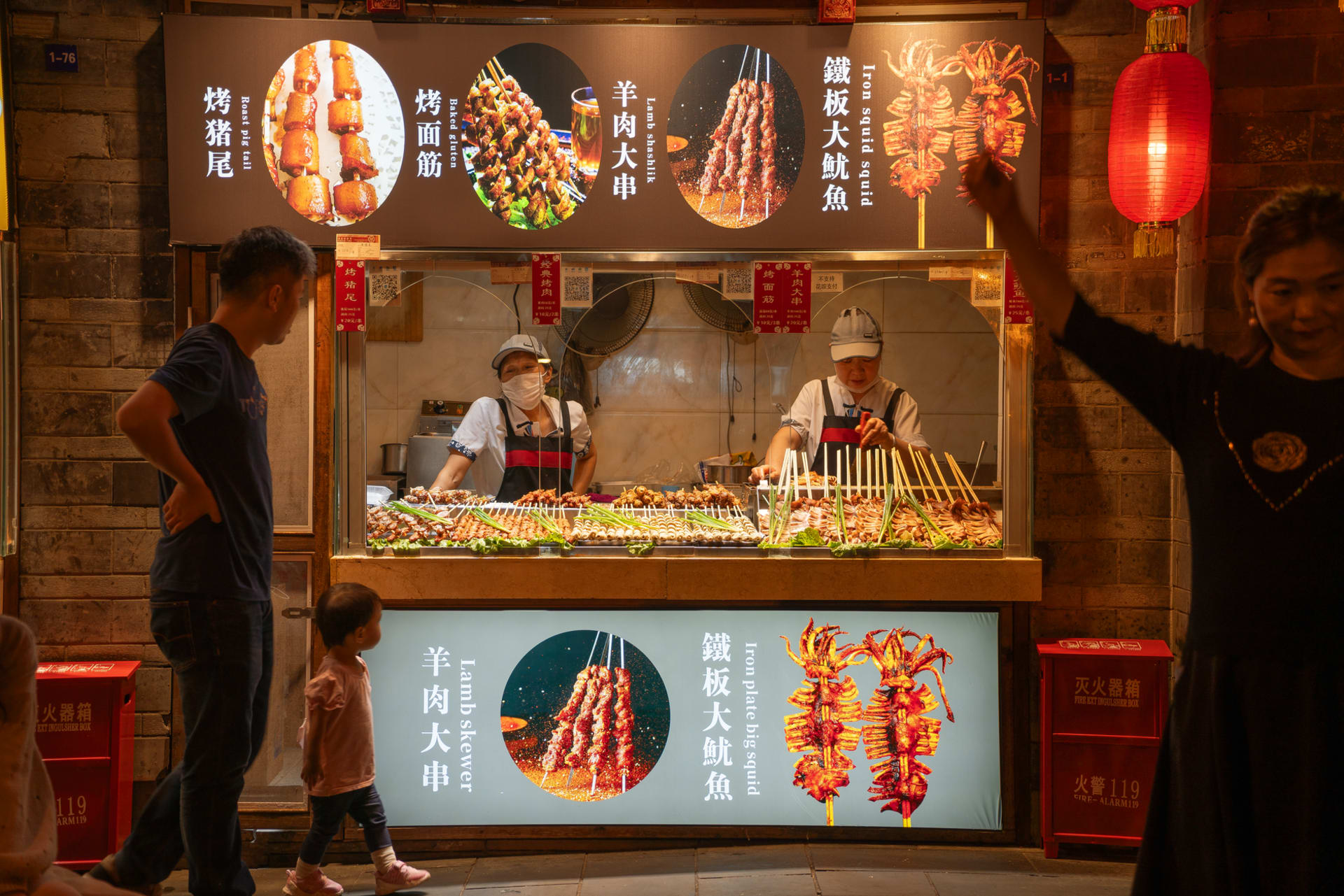 Jinli old street at dusk in Chengdu, red lanterns glowing above carved wooden storefronts lining a stone-paved lane