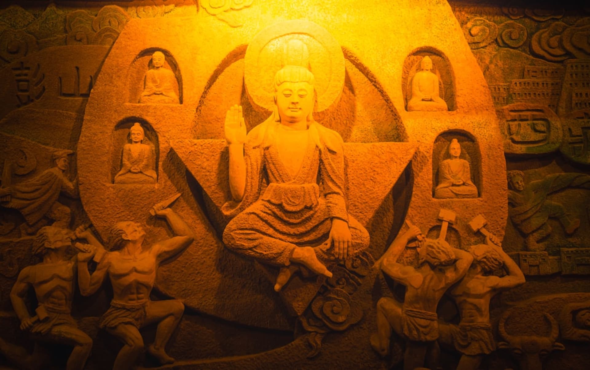 The colossal Leshan Giant Buddha rising from the red sandstone cliff above the confluence of three rivers, monks' statues flanking the staircase cut into the rock