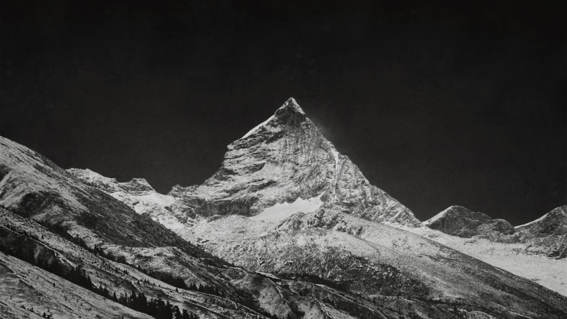 The four snow peaks of Siguniang Shan rising above a valley of white-trunked birch trees and a glacial stream catching morning light, prayer flags in the foreground