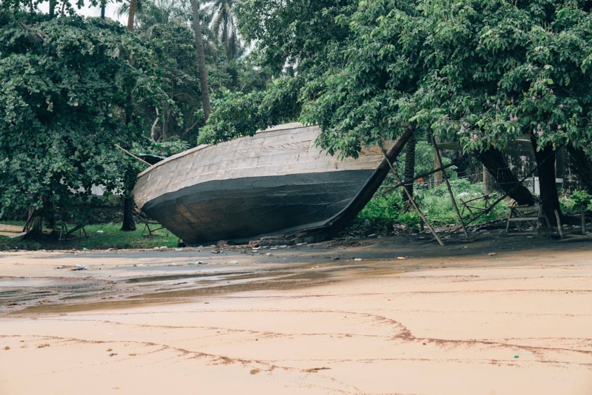 Une pirogue en bois tirée sur une plage de sable blanc à Dublin Island, la jungle pressée jusqu'au bord de l'eau sous une légère brume matinale