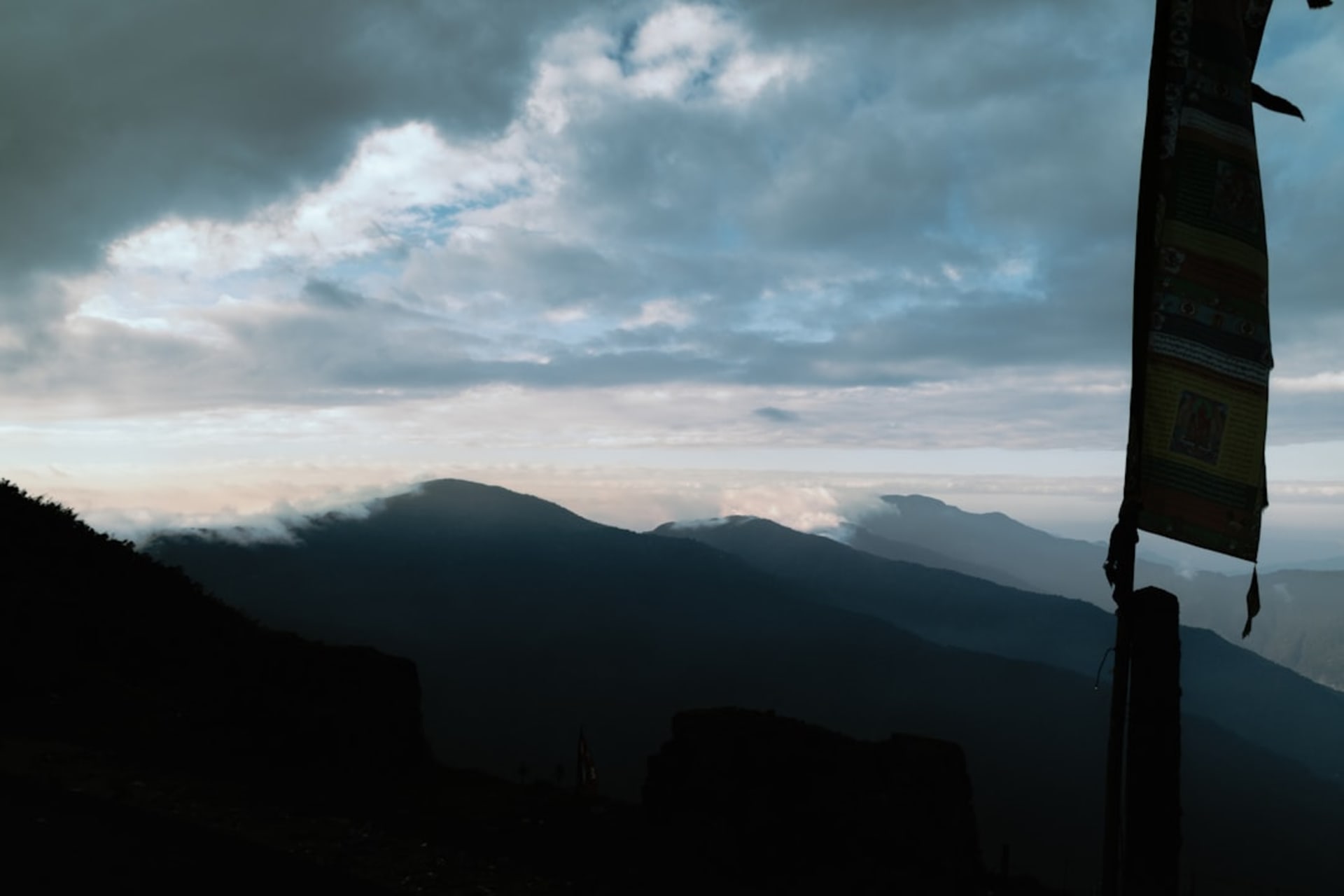 The Zuluk zigzag road seen from above at dawn, switchbacks descending through pine forest into cloud, Kangchenjunga on the horizon