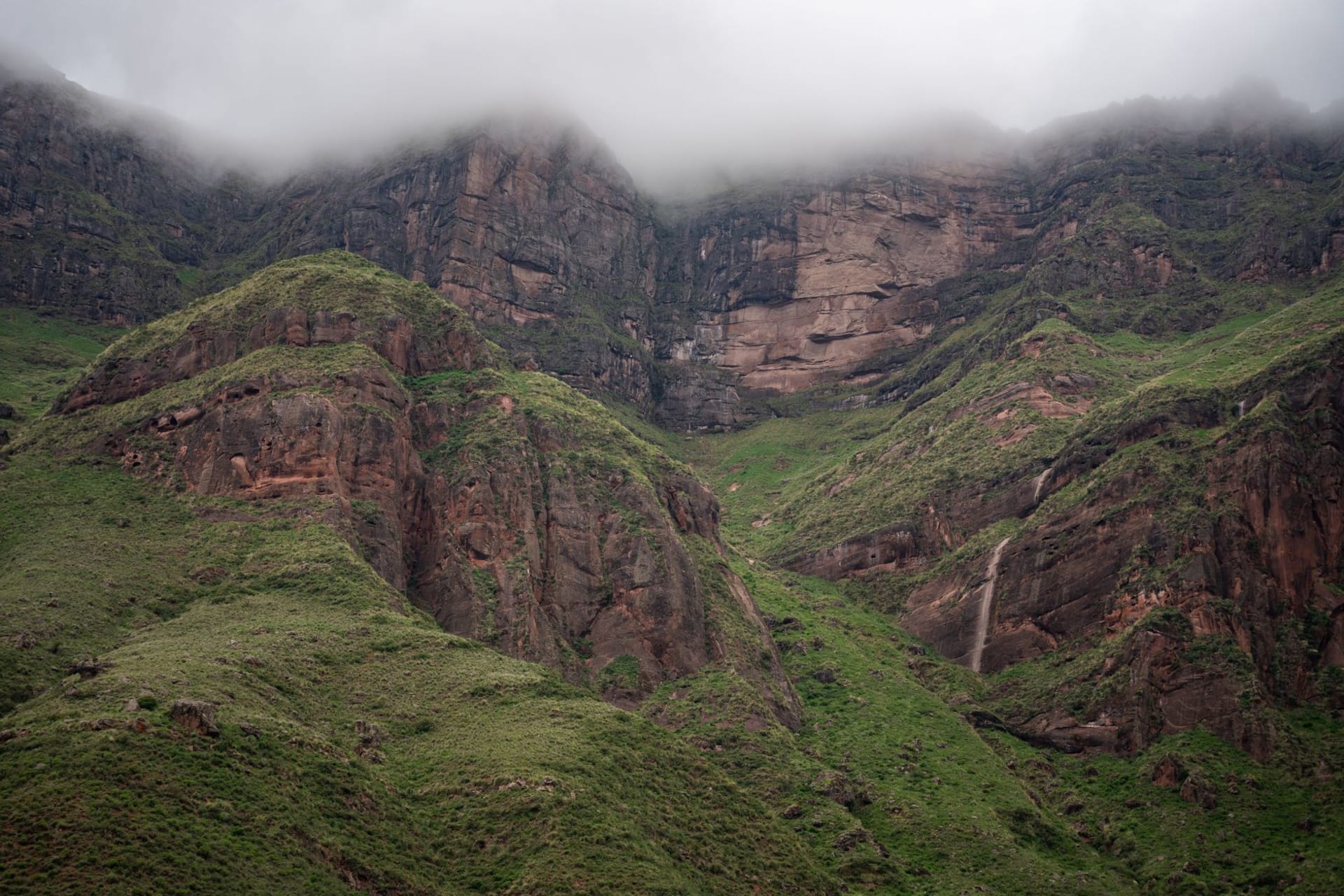 The flat grassy summit of Inatye in Ethiopia's Simien Mountains ending abruptly at a sheer escarpment, with jagged pinnacles and deep valleys stretching to the hazy horizon