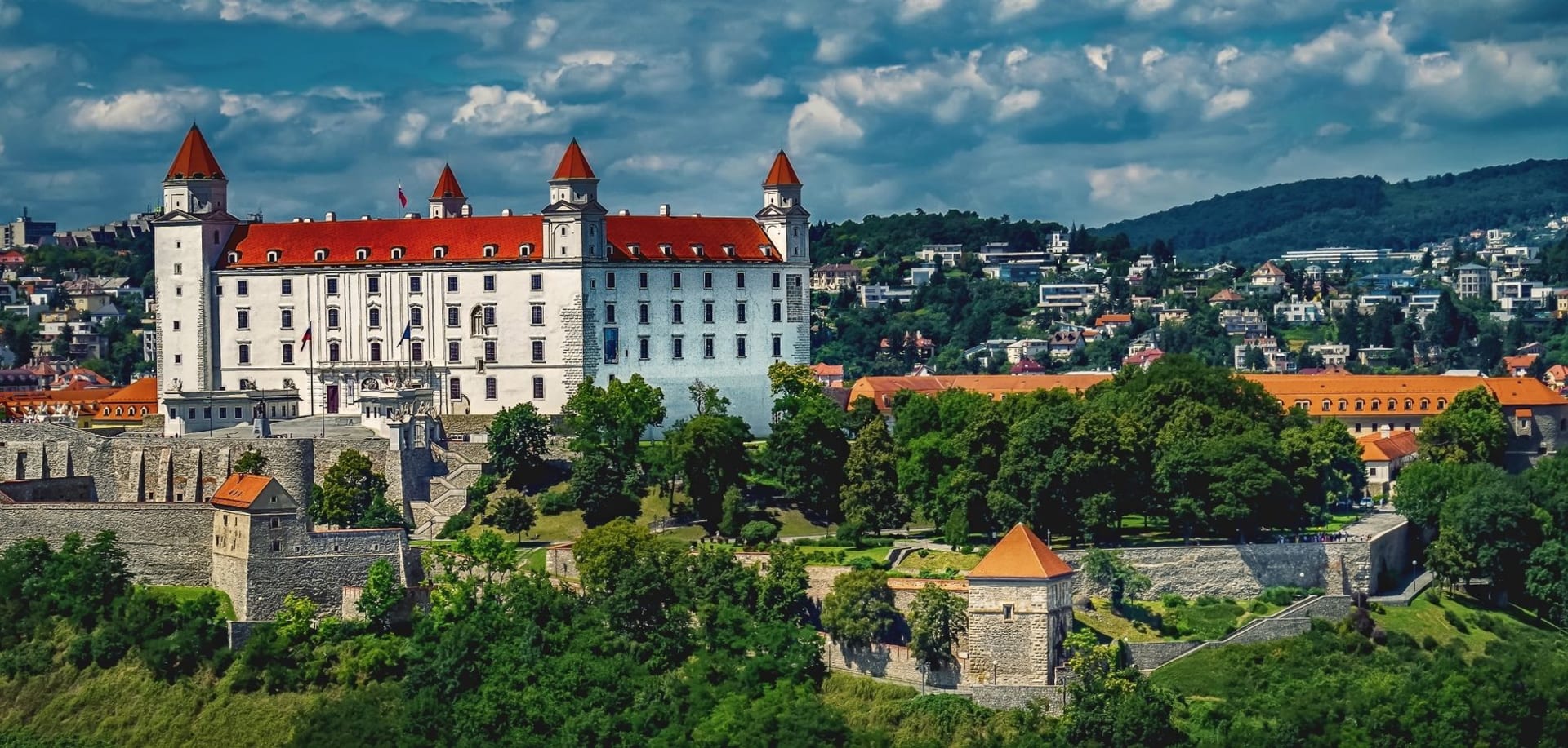 El Castillo de Bratislava sobre la ciudad, rodeado de un denso dosel de bosque bajo un cielo despejado
