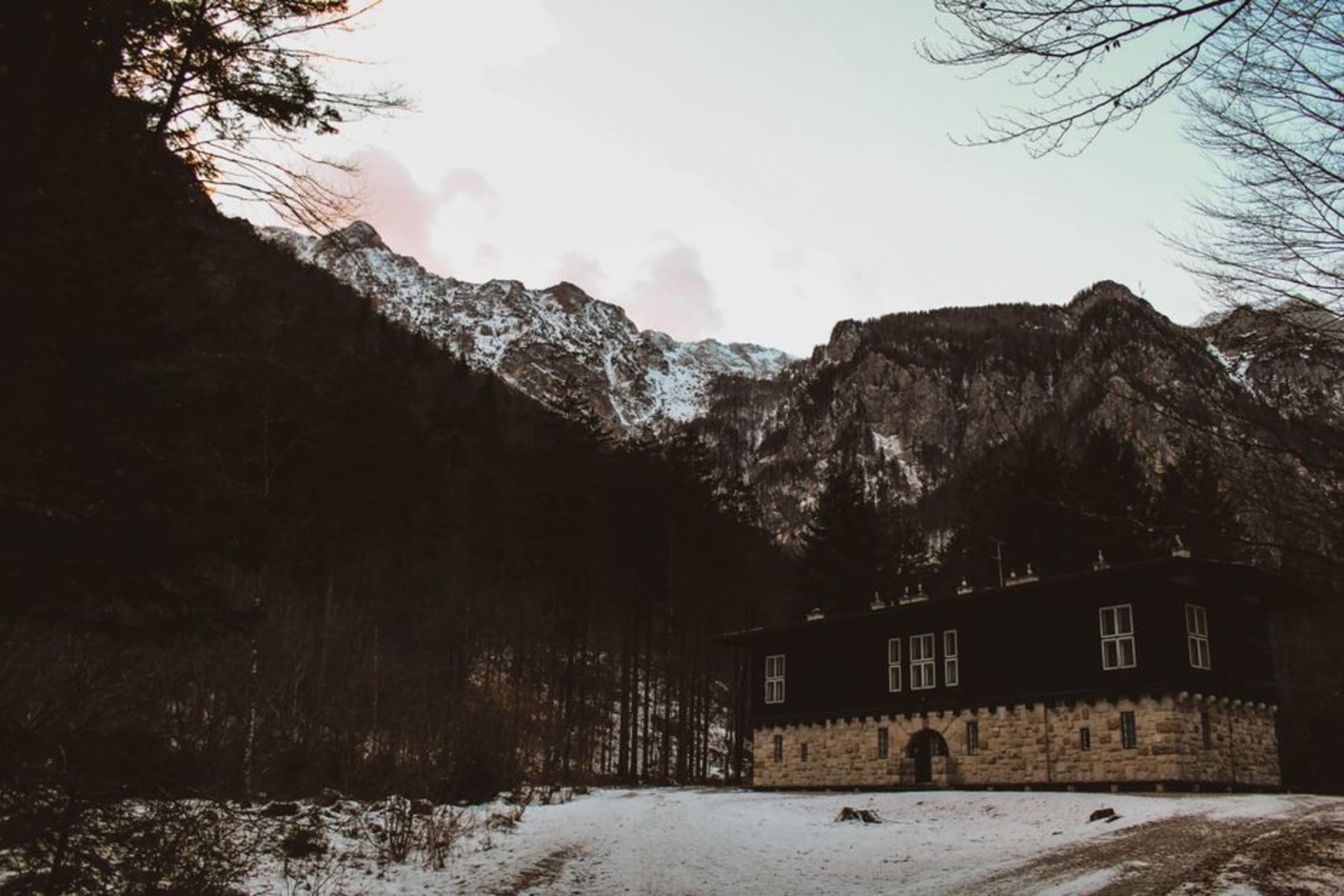 The Kamniška Bistrica river emerging clear and fast from a forested alpine valley, with the sheer limestone peaks of the Kamnik-Savinja Alps rising directly behind