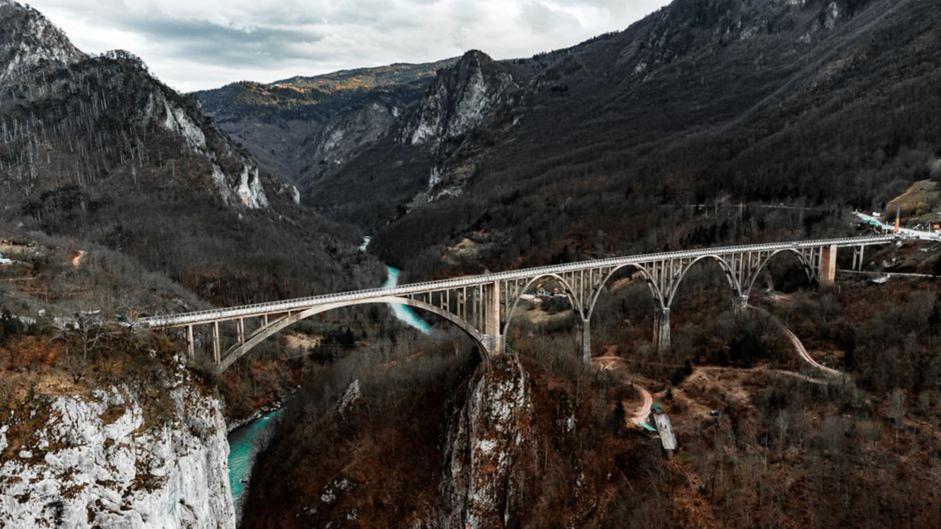 La confluencia en forma de Y de los ríos Soča e Idrijca formando un lago turquesa en Most na Soči, visto desde una ladera con un puente de piedra cruzando por debajo