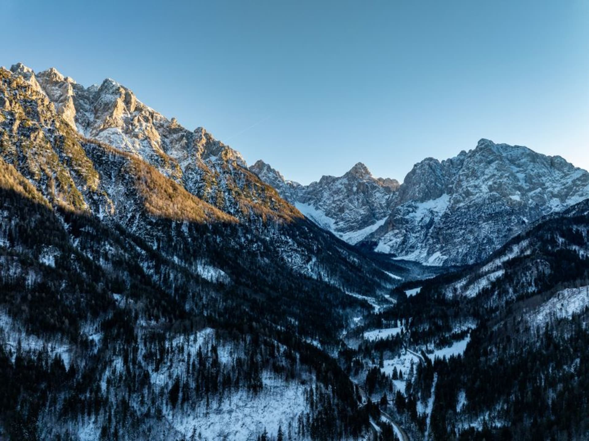 La vallée glaciaire étroite de Robanov Kot avec des séchoirs à foin traditionnels slovènes et des fermes se dressant contre les sommets calcaires abrupts des Alpes de Savinja