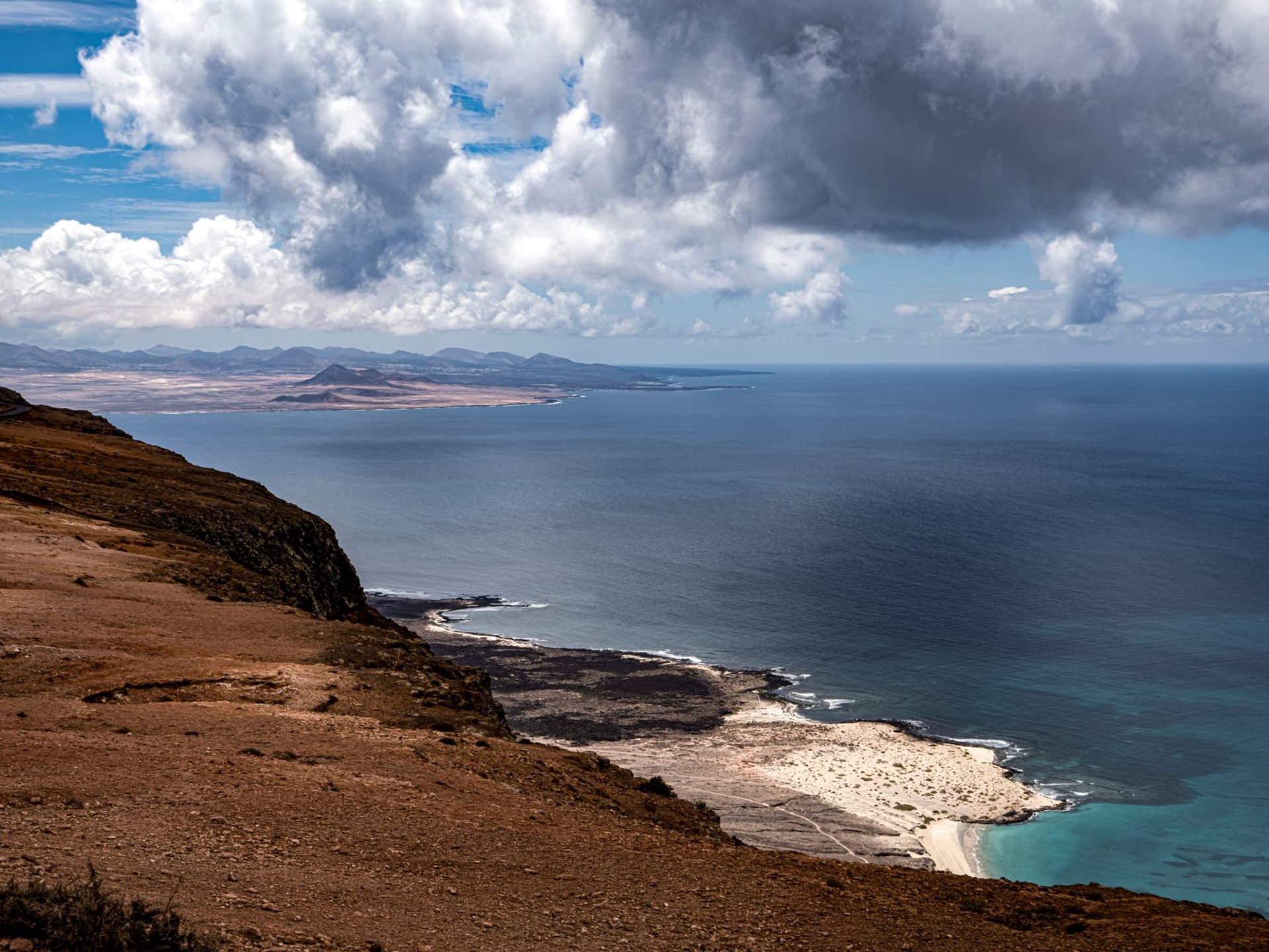 Rocky limestone headland of Cape Guardafui at sunset where Gulf of Aden meets Indian Ocean, lighthouse visible on the highest point against a copper sky