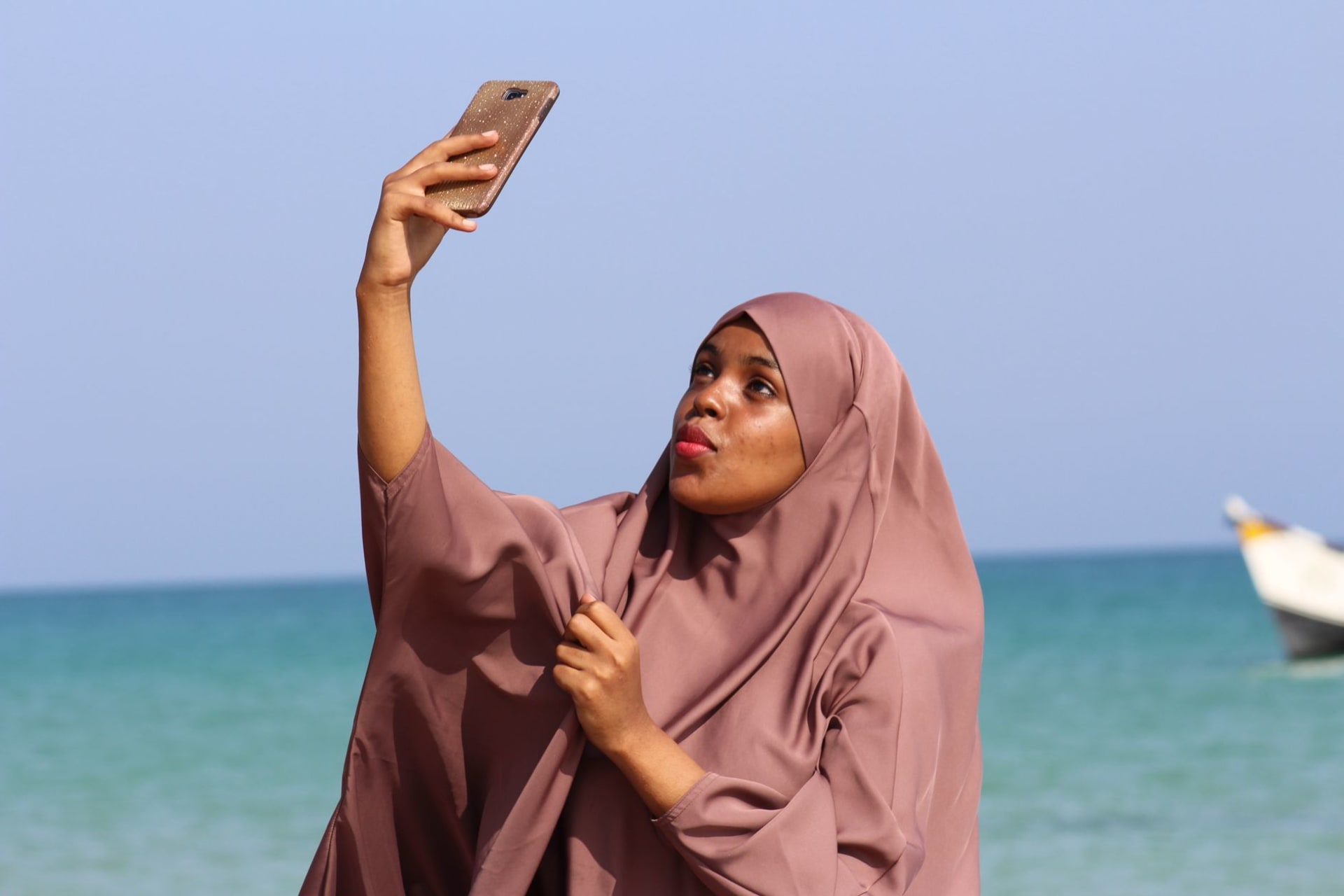 Wide white beach at Kismayo's southern shore at late afternoon, traditional fishing boats beached above the tide line, Indian Ocean flat and pale blue