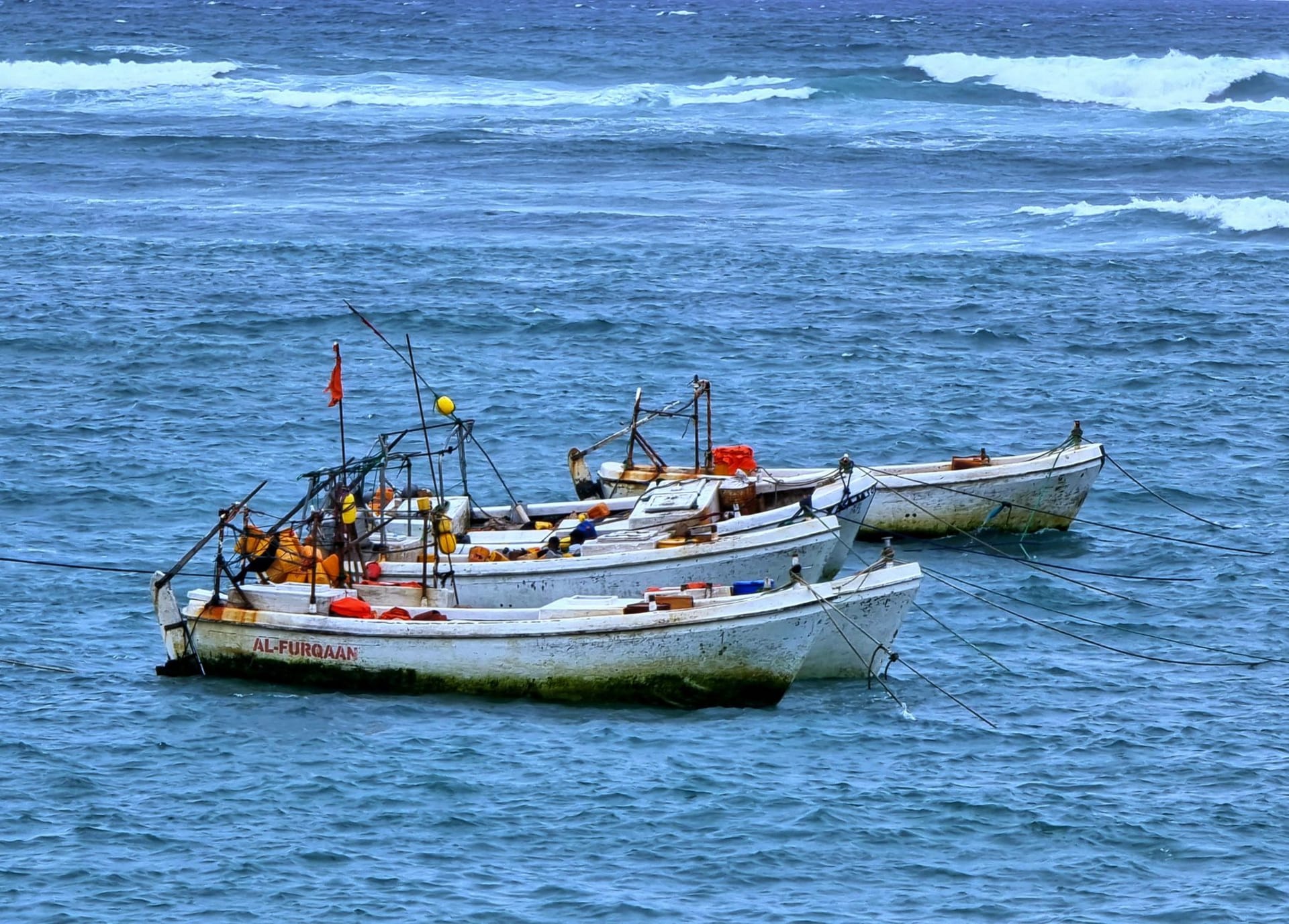 Wooden fishing boats moored on the blue waters near Mogadishu, with the calm of the Indian Ocean stretching behind them