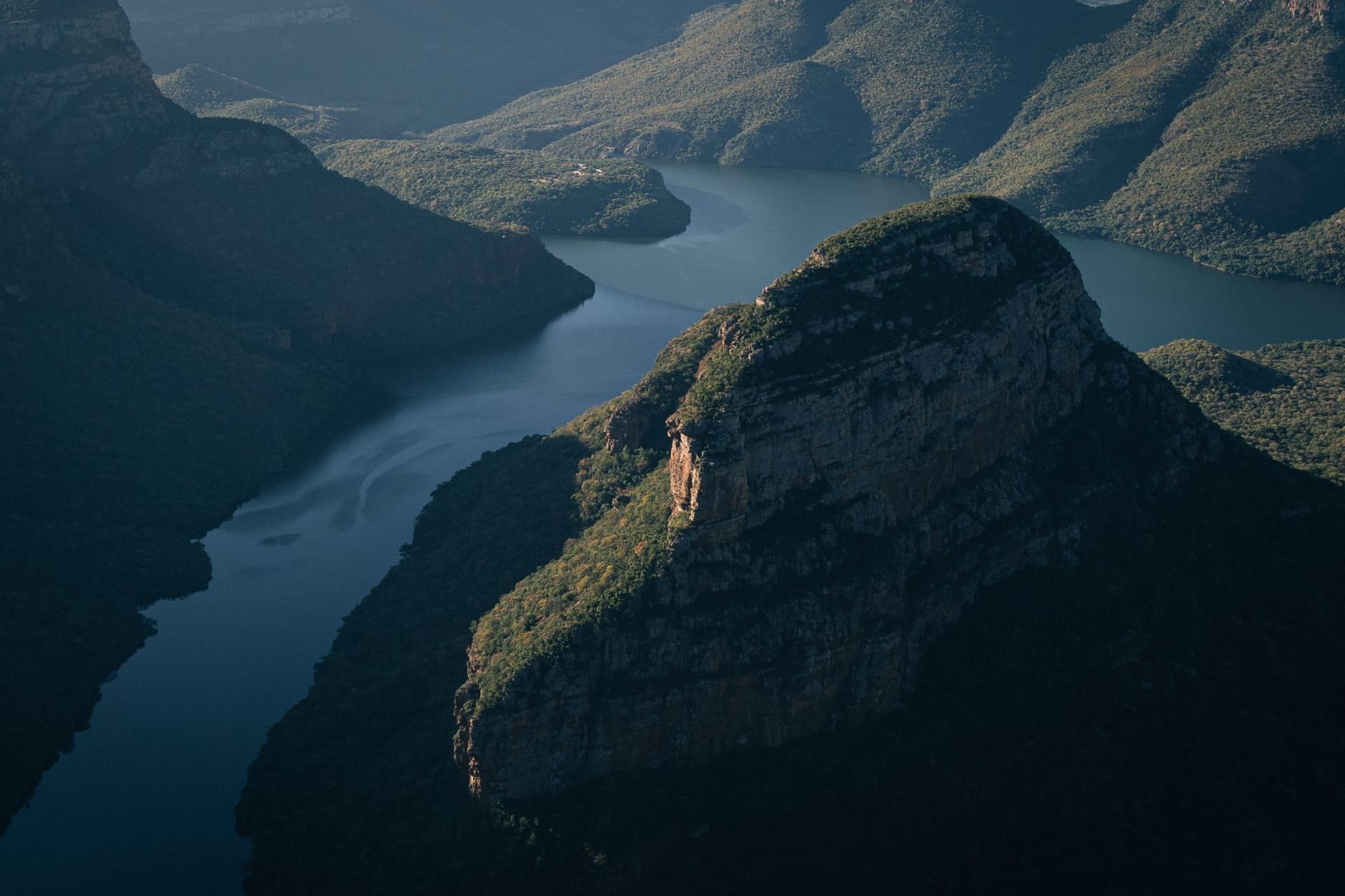 The Three Rondavels of Blyde River Canyon, three round green-topped peaks rising above the jade Blyde River far below, under a sky of drifting cloud