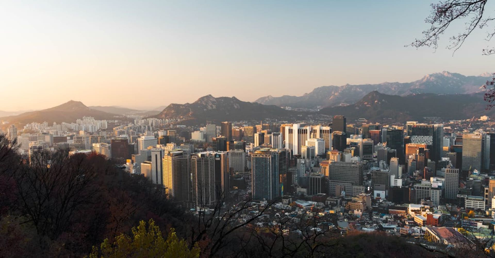 Neon signs and bustling crowds in a Seoul nightlife district with mountains behind