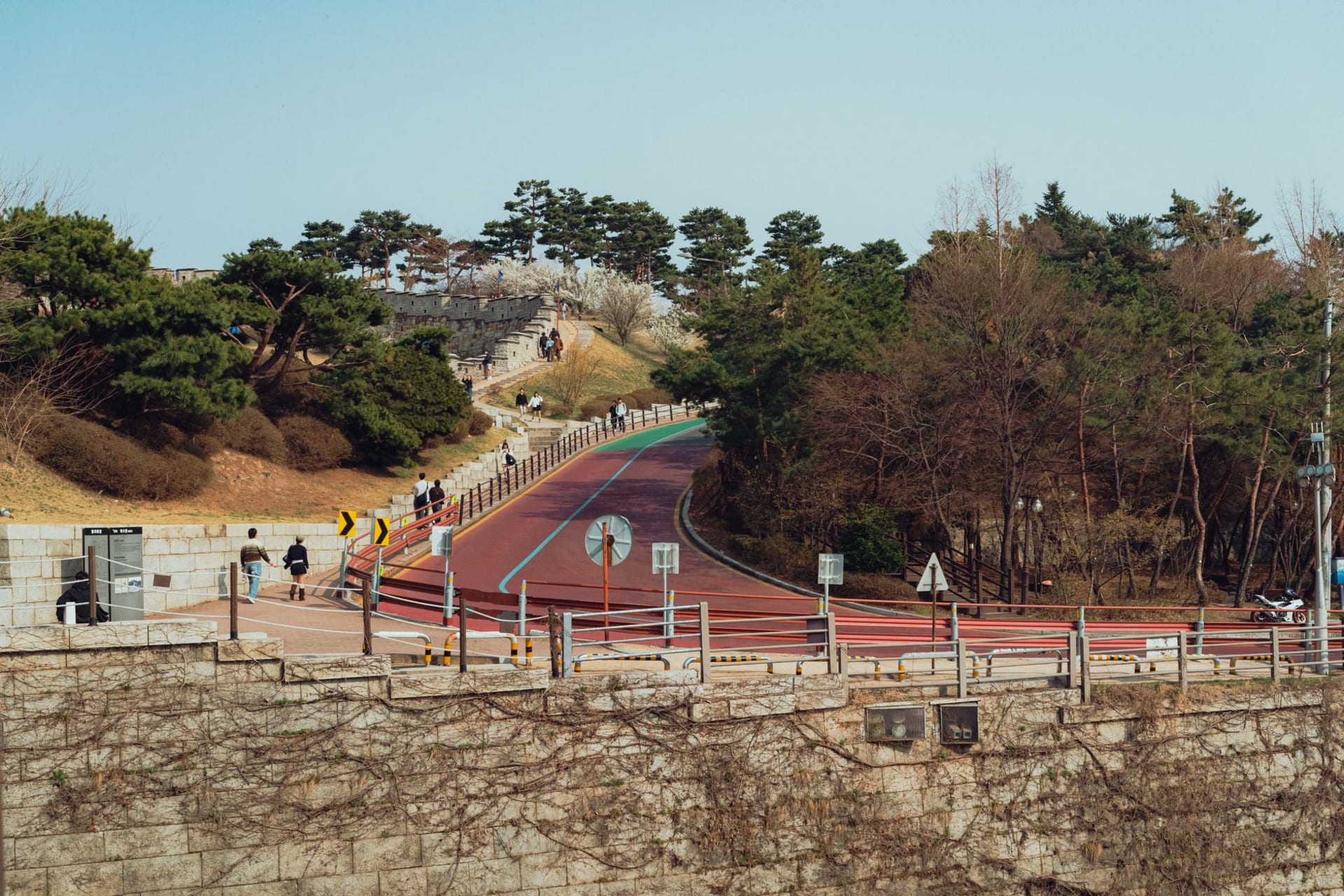 The floodlit stone-and-brick wall of Hwaseong Fortress curving over a hill in Suwon at dusk, the Paldalmun gate and a guard pavilion silhouetted against the sky